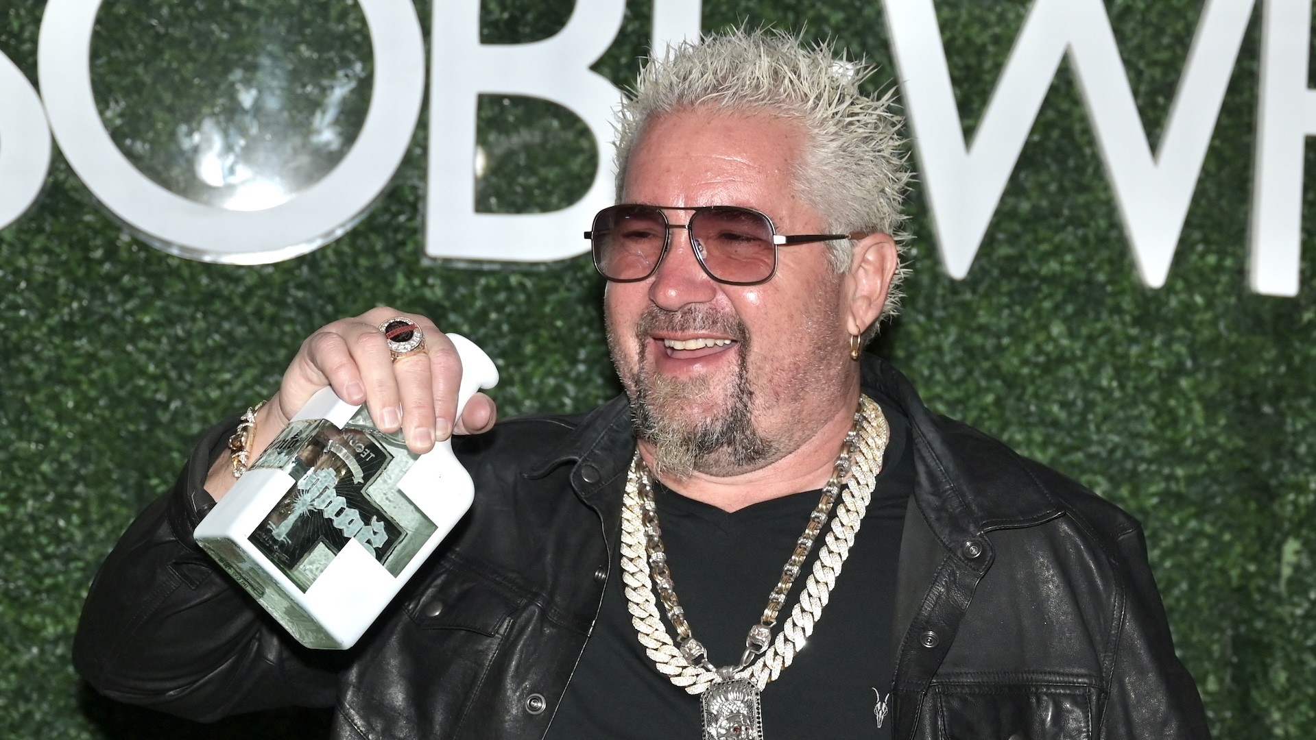 Guy Fieri photographed holding a bottle of Santo Tequila.