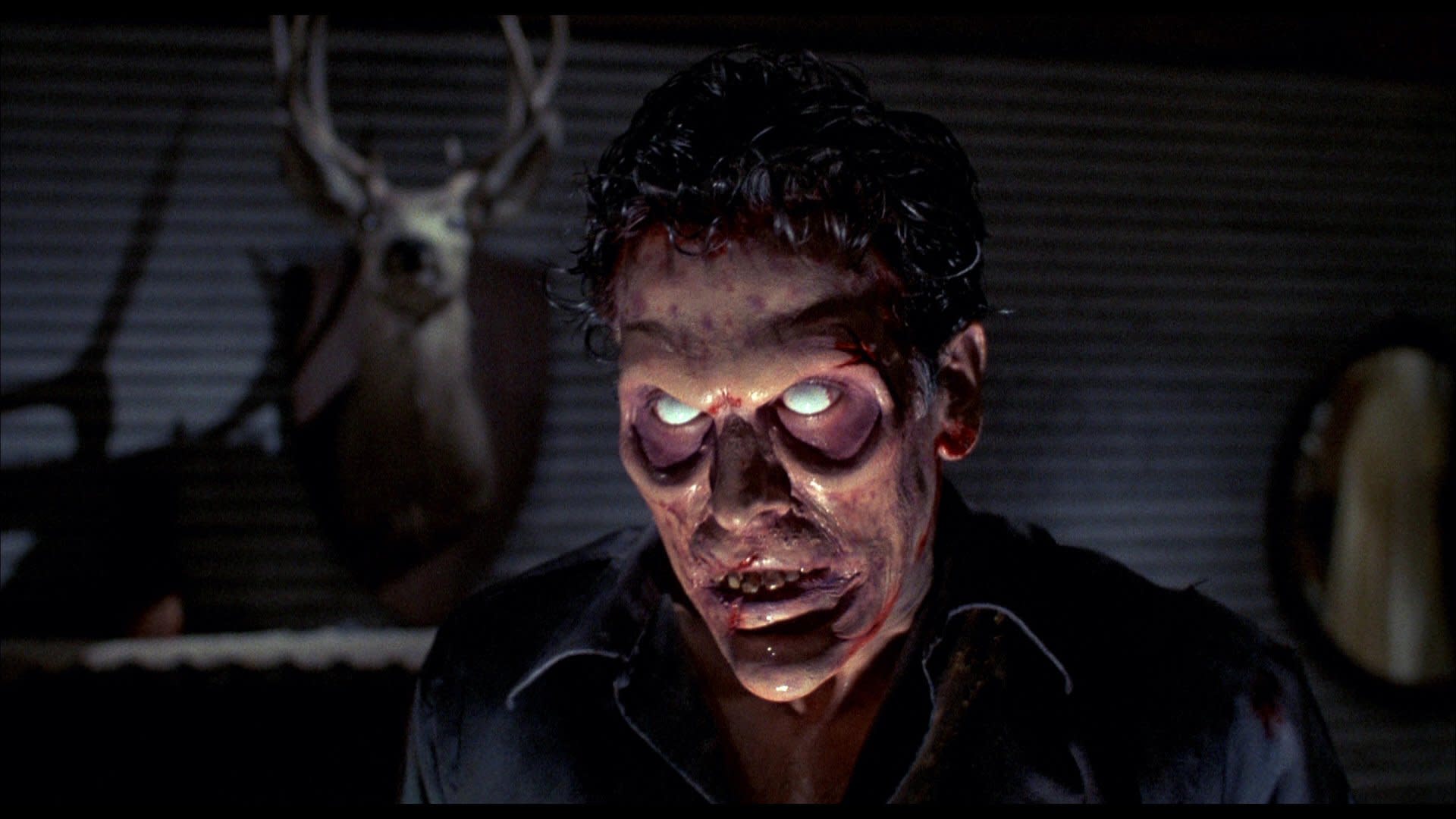A zombie-like figure with glowing eyes in a dimly lit room, a deer head mounted on the wall behind.