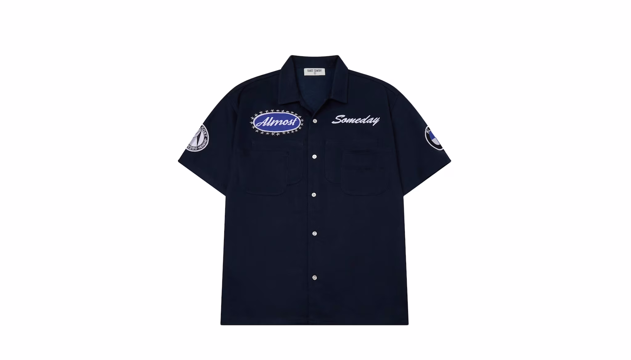 A navy blue button-up shirt with patches reading "Almost" and "Someday" on the front, featuring short sleeves and a collar.