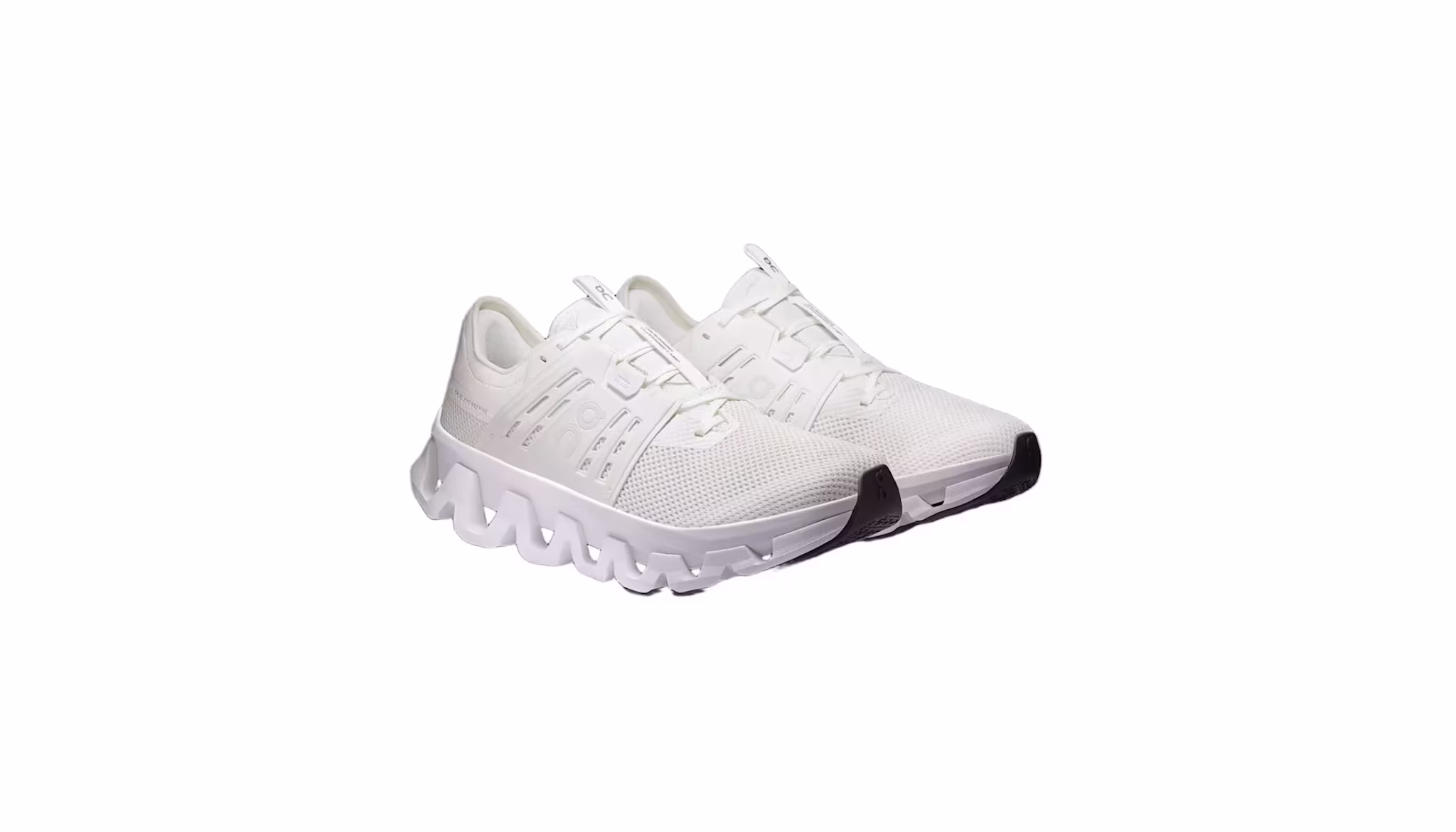 A pair of white athletic sneakers with a unique, wavy sole design and black toe accents.
