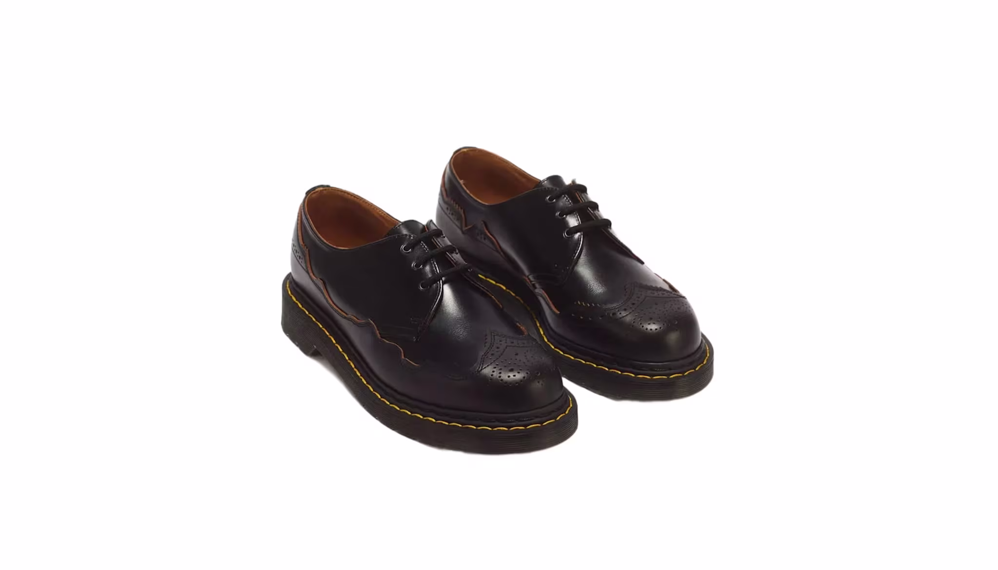 A pair of black leather brogue shoes with yellow stitching and thick soles.