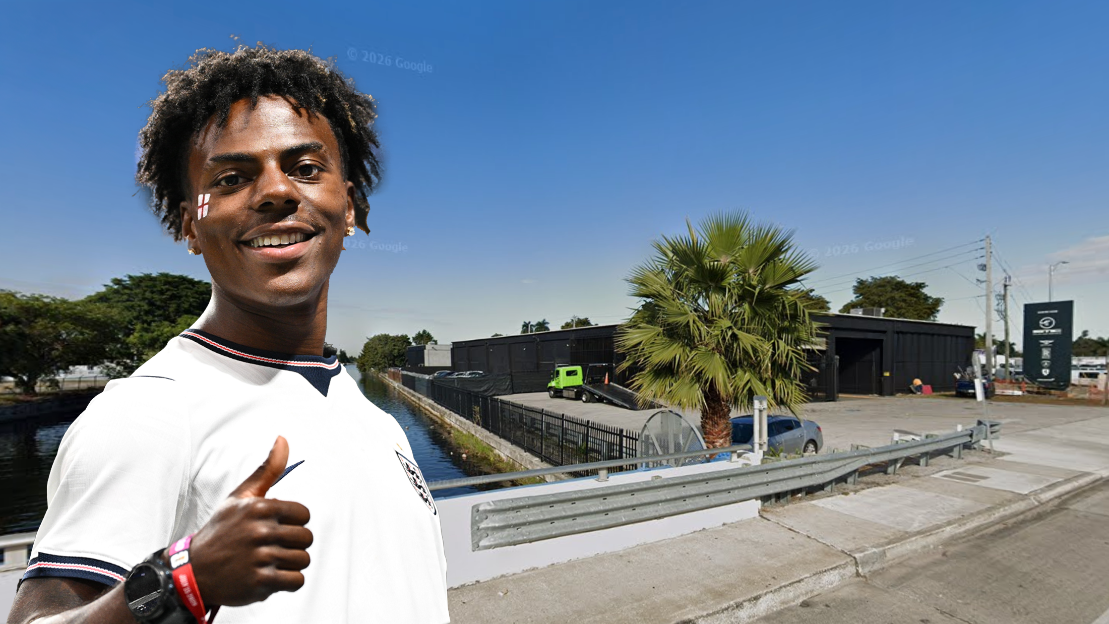 A person in a white shirt giving a thumbs up, standing near a road with a palm tree and industrial buildings in the background.