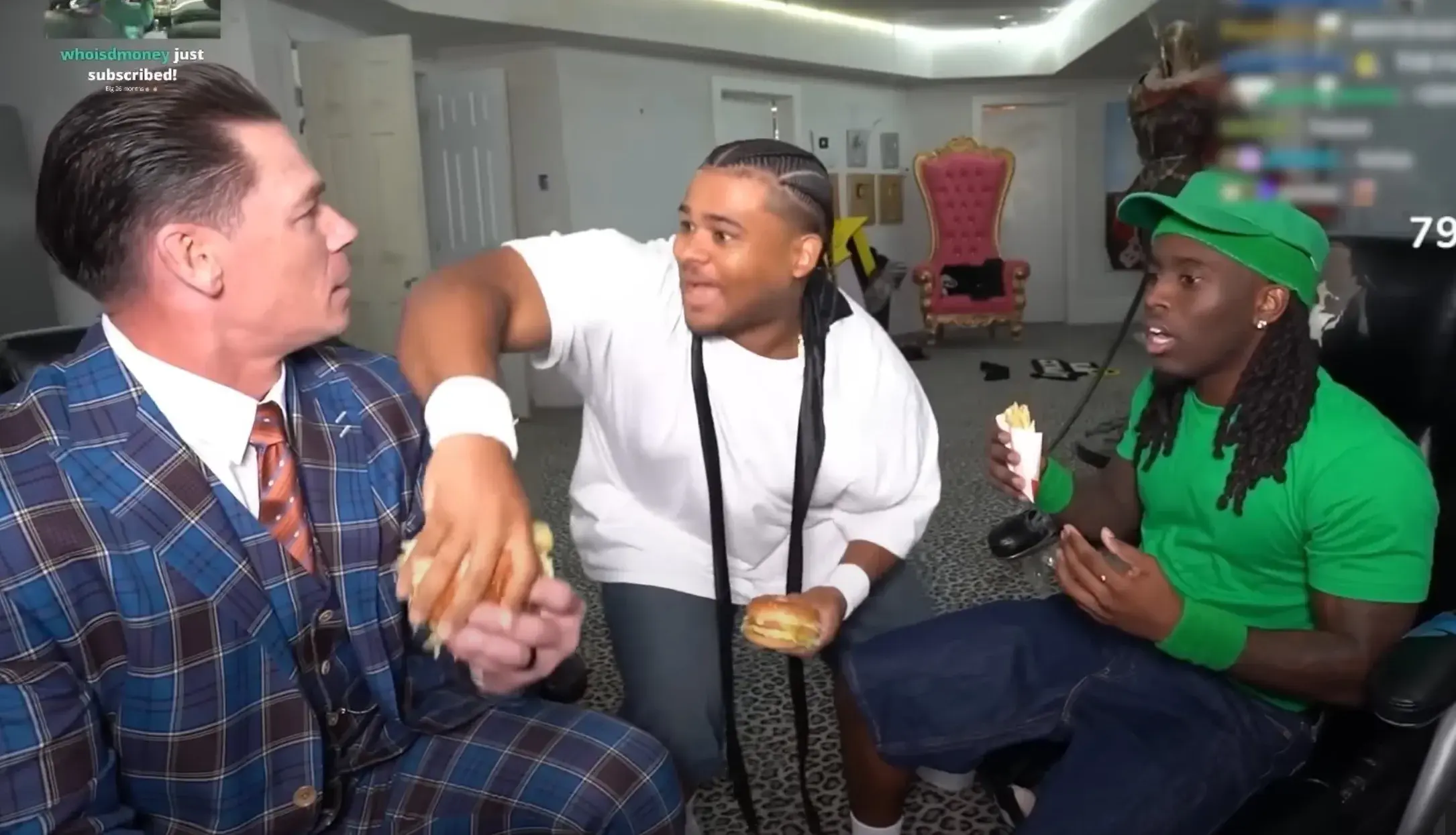 Fanum, Kai Cenat, and Jon Cena in a room, one in a plaid suit holding a burger, another in a white shirt, and the third in a green outfit with a cap.