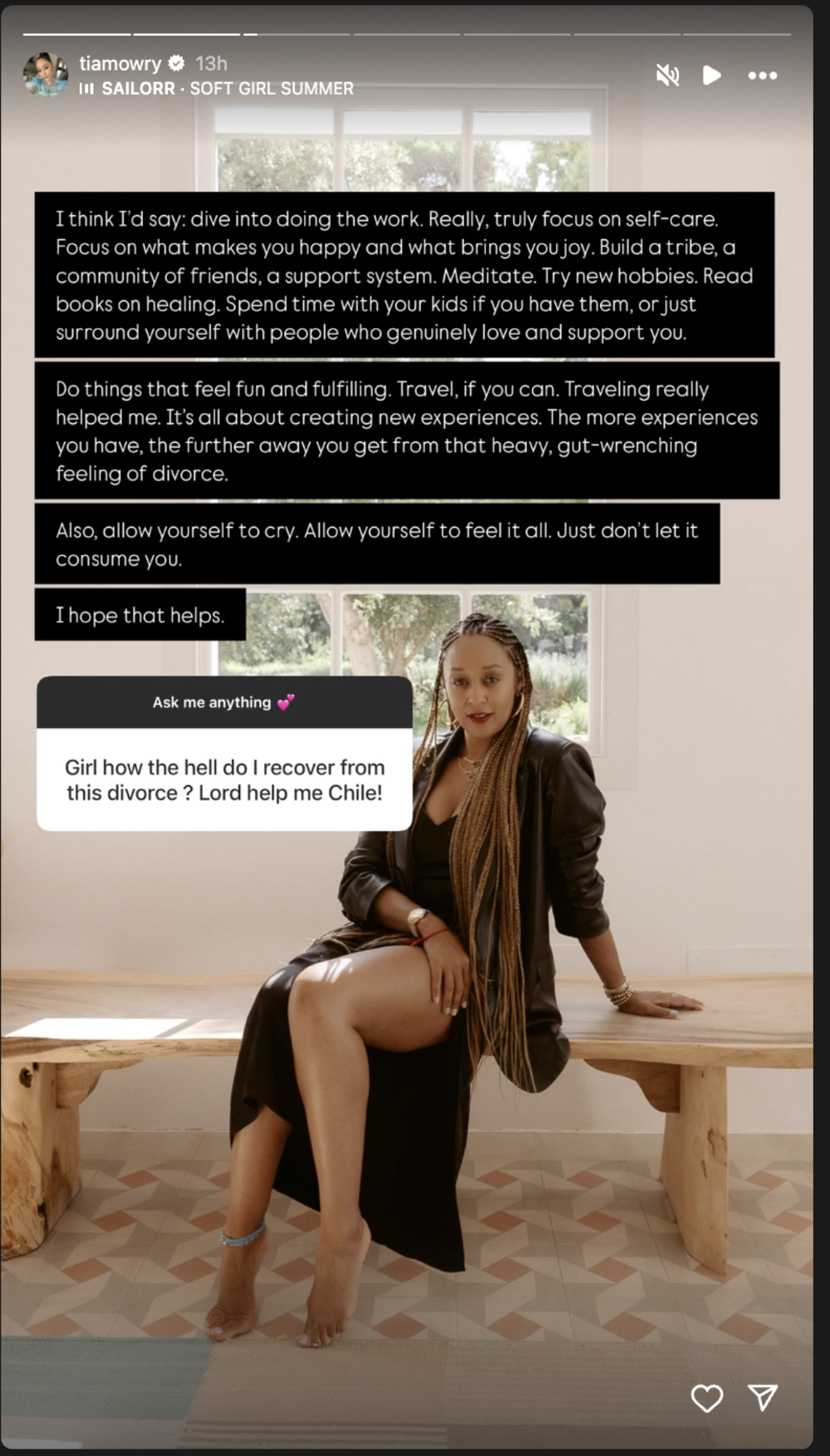 Tia Mowry sits on a bench, offering advice on healing from divorce. She's dressed in black with long braids, in a bright room.