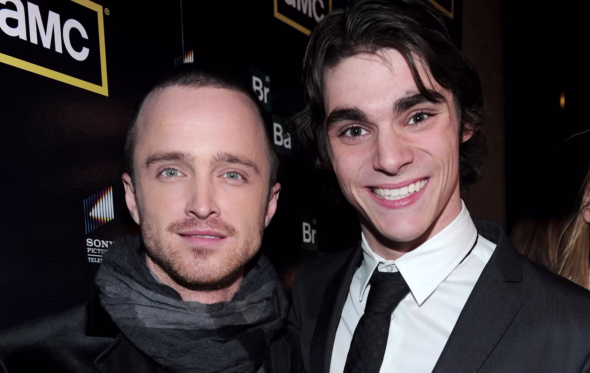 Aaron Paul and RJ Mitte at an AMC event, both wearing suits and smiling.