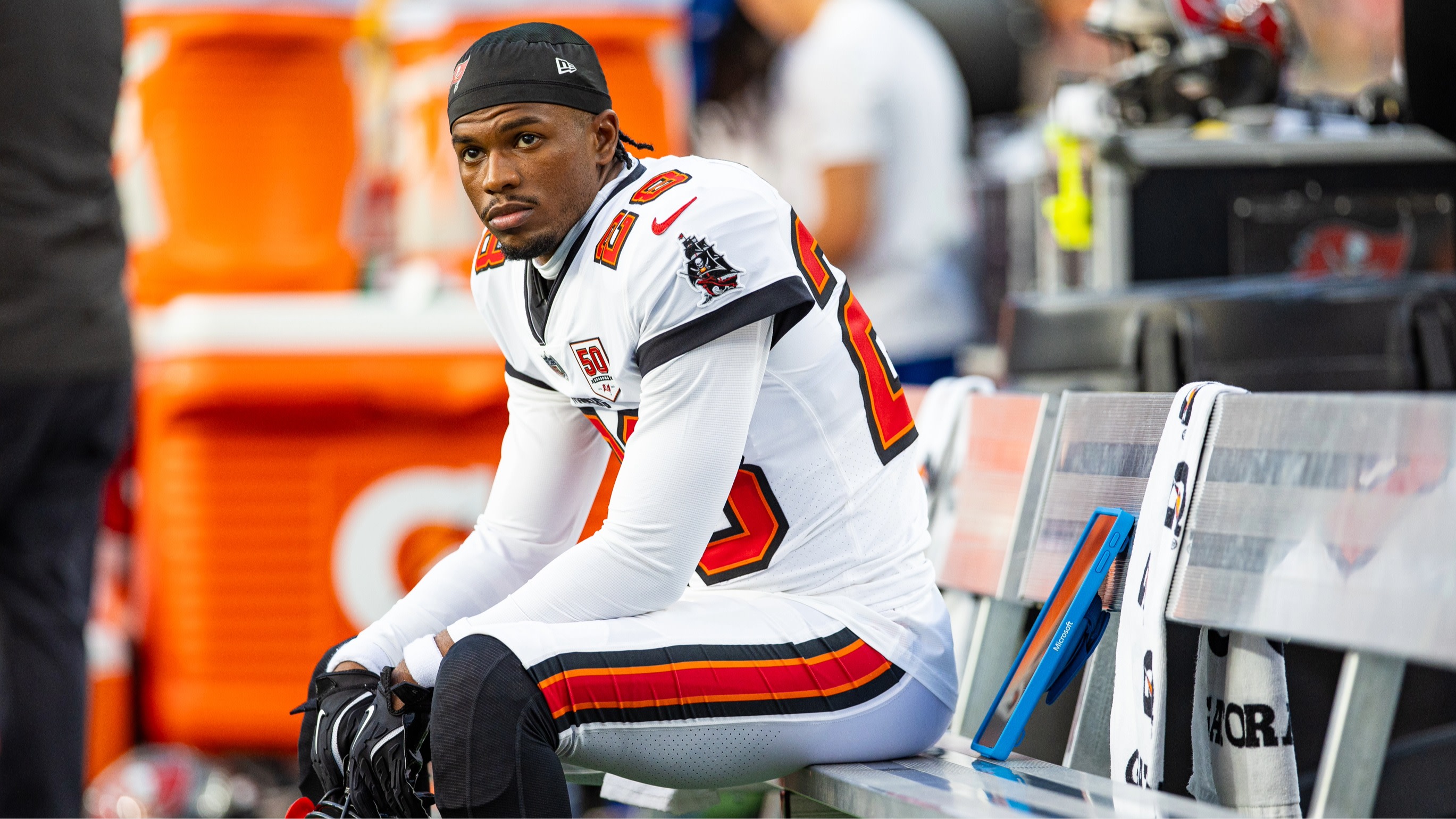 Shiloh Sanders in a Tampa Bay Buccaneers uniform sits on a bench, looking pensive.