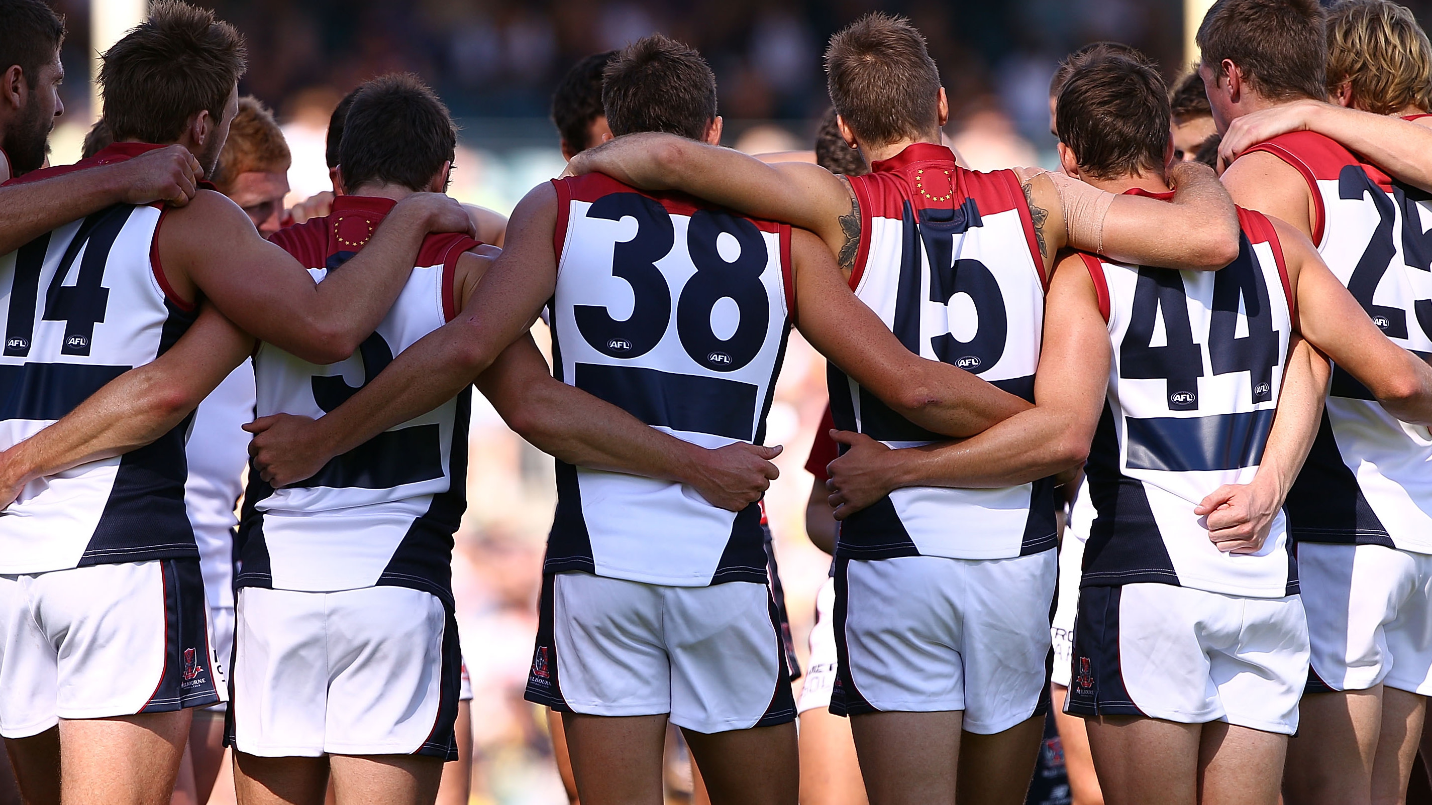 Melbourne players form a huddle before the first bounce wearing tops with blacked out sponsor logos during the round two AFL match between the West Coast Eagles and the Melbourne Demons