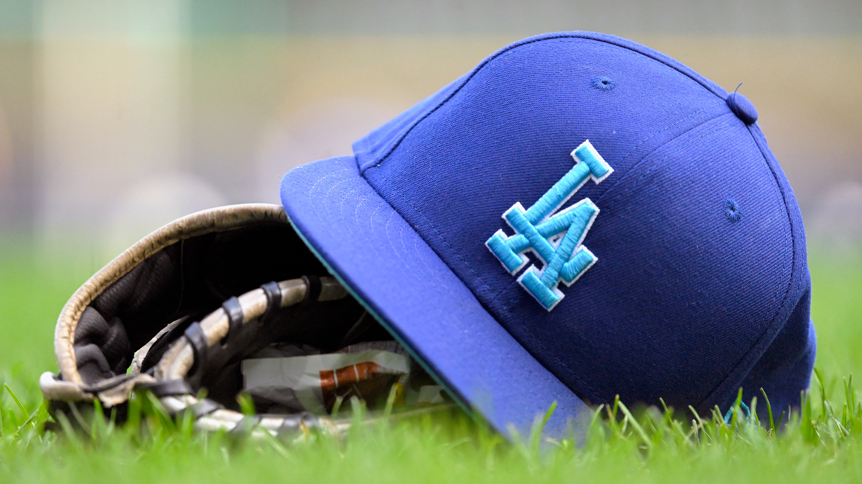 A Los Angeles Dodgers hat sits on a a baseball glove during a MLB game between the Milwaukee Brewers and Los Angeles Dodgers on August 12, 2024, at American Family Field in Milwaukee, WI.