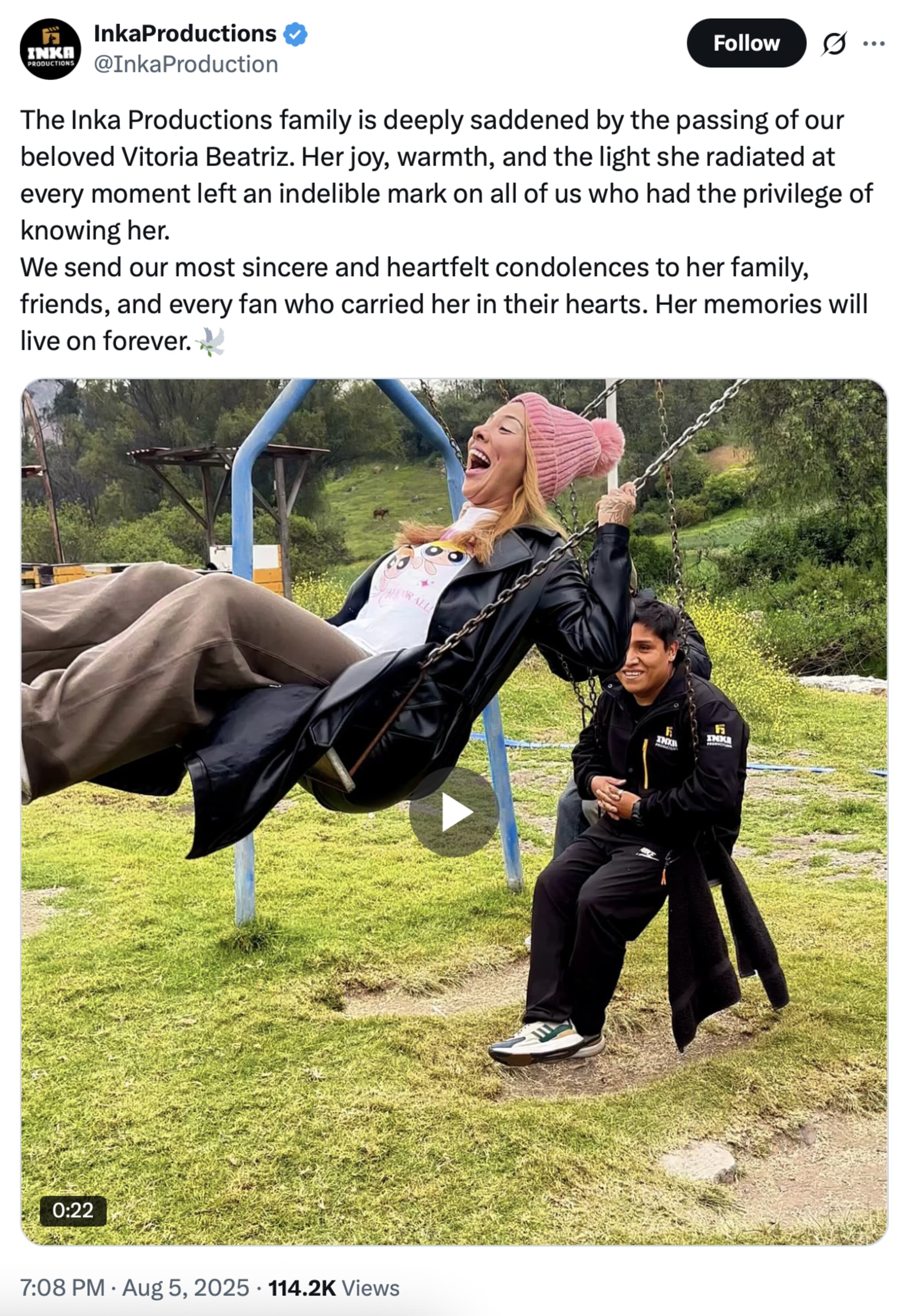 A woman joyfully swings on a swing set, pushed by a man. They are outdoors on a grassy area, both smiling.