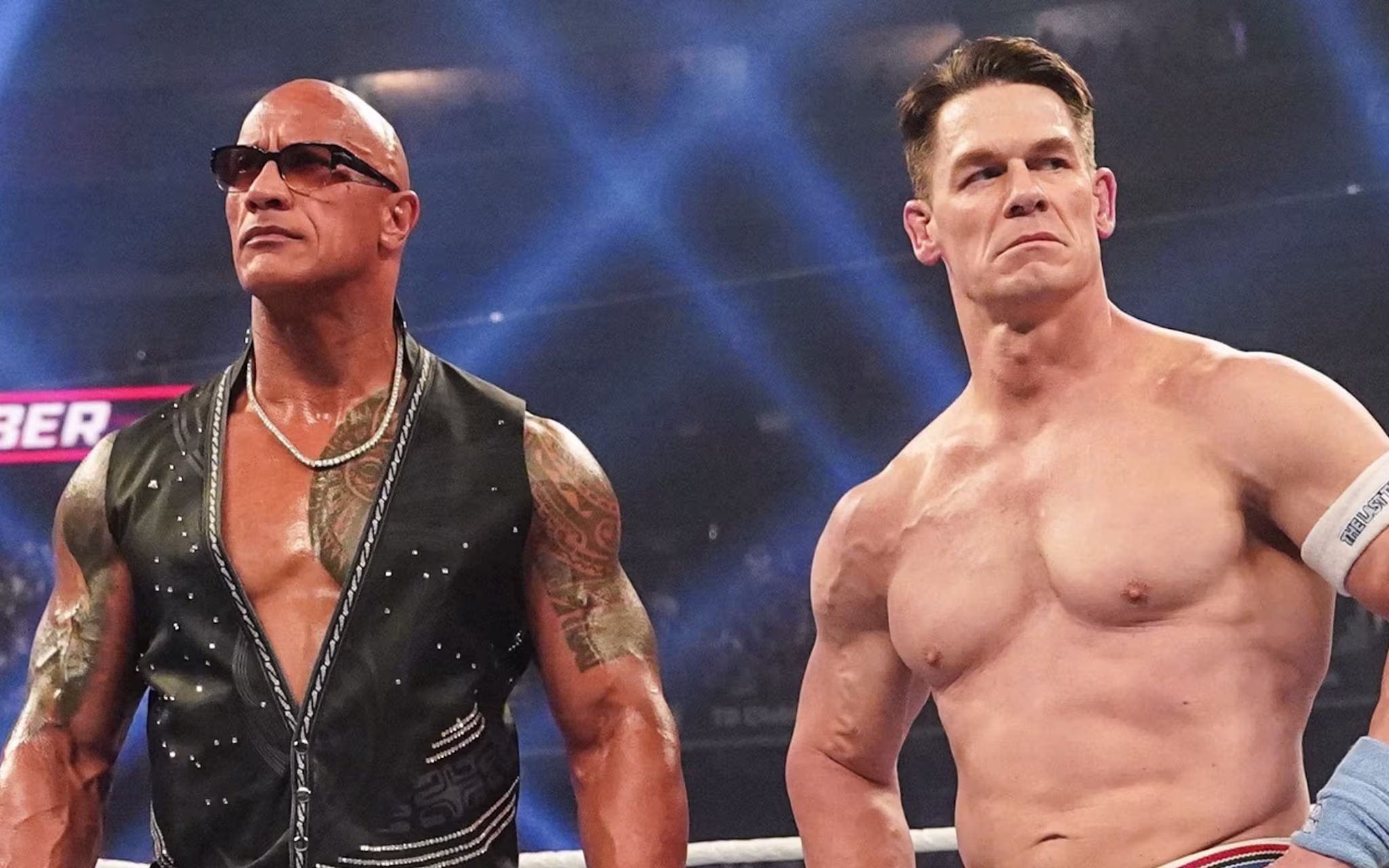 Dwayne "The Rock" Johnson and John Cena in a wrestling ring, both looking serious.