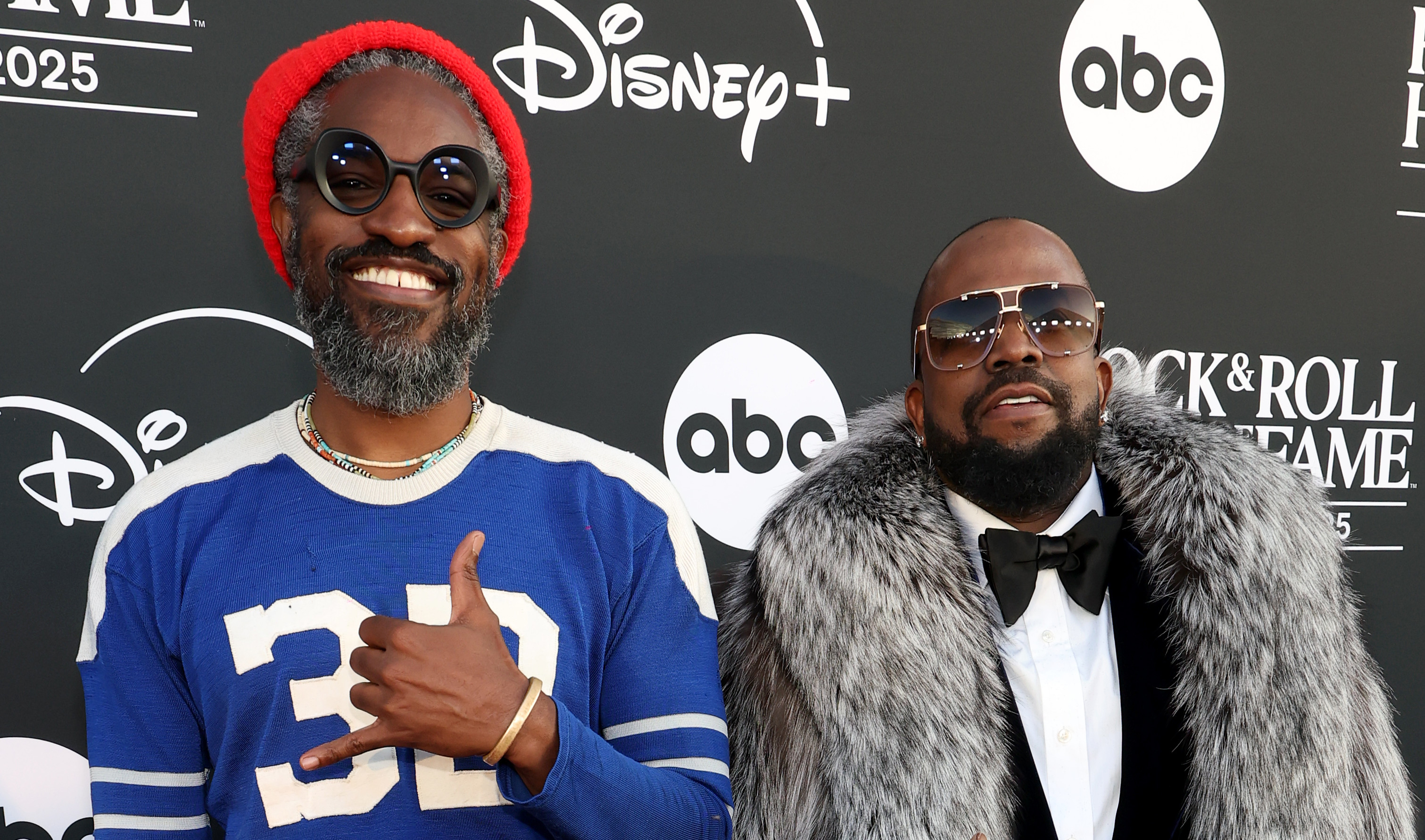 OutKast on the red carpet; Andre 3000 in a blue jersey and red beanie, Big Boi in a fur coat and sunglasses.