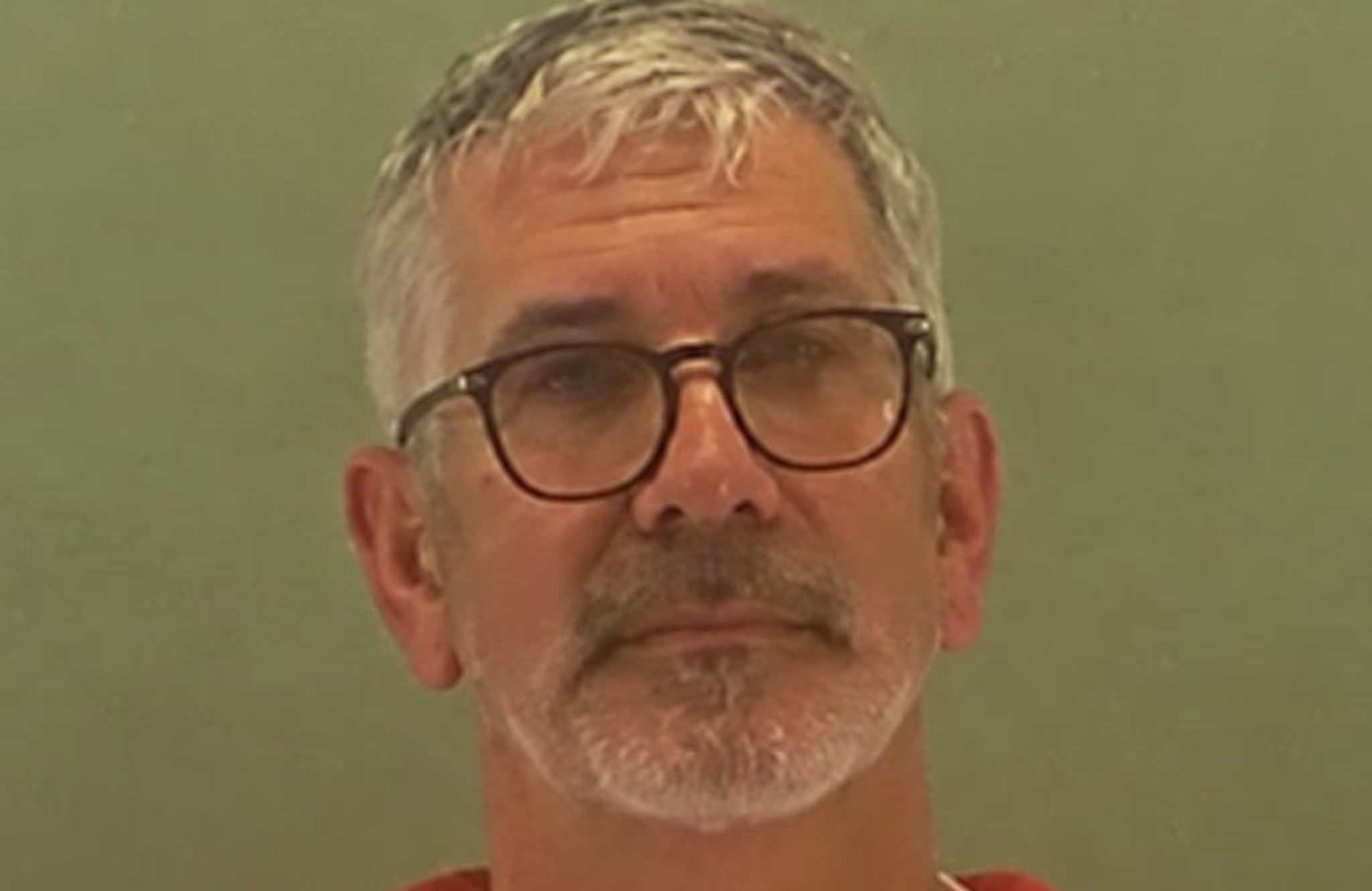 Terry Ward with gray hair, glasses, and a beard, wearing a red shirt, against a plain background.