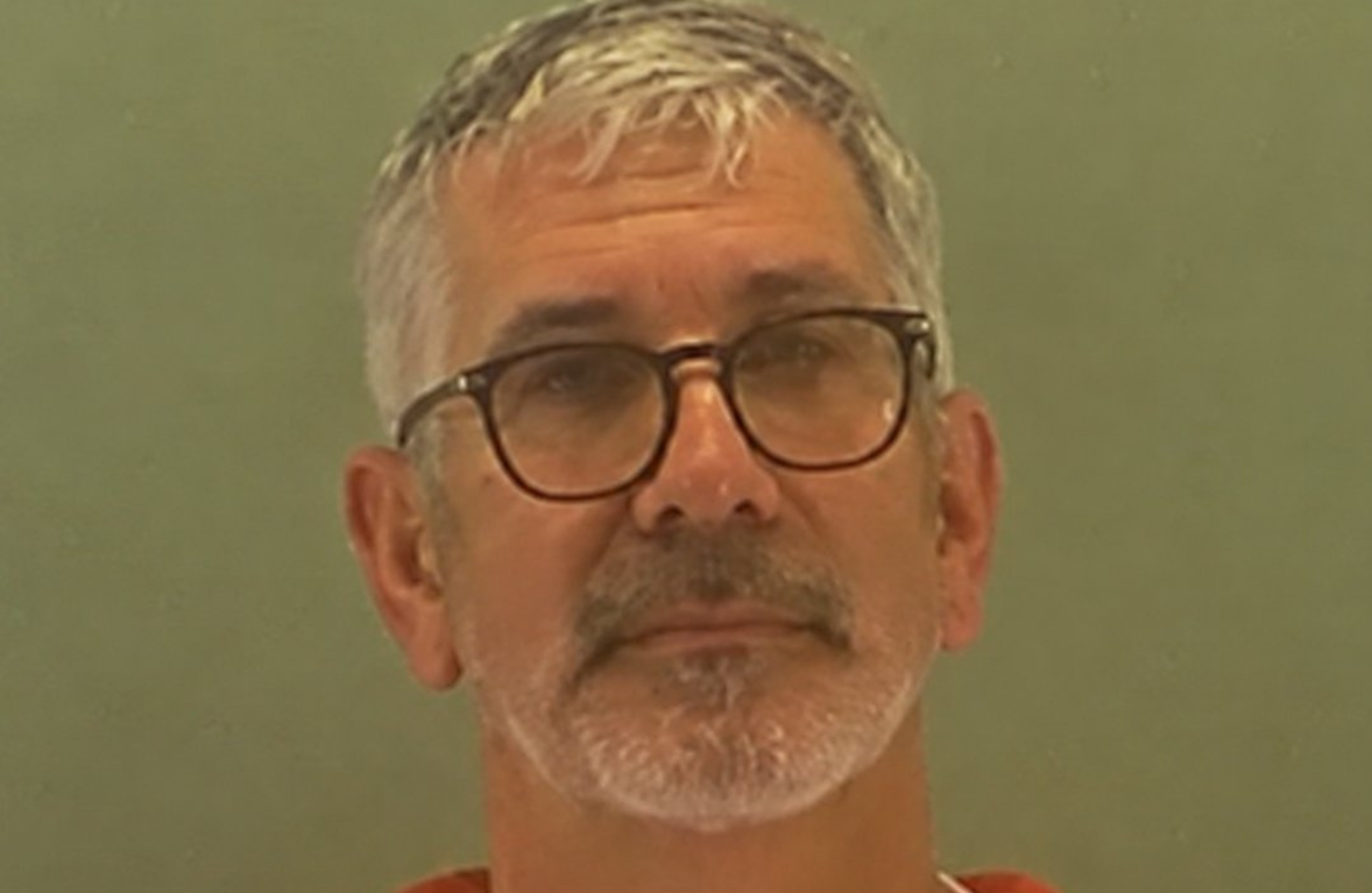 Terry Ward, with gray hair, glasses, and a beard, looks straight ahead against a plain background.
