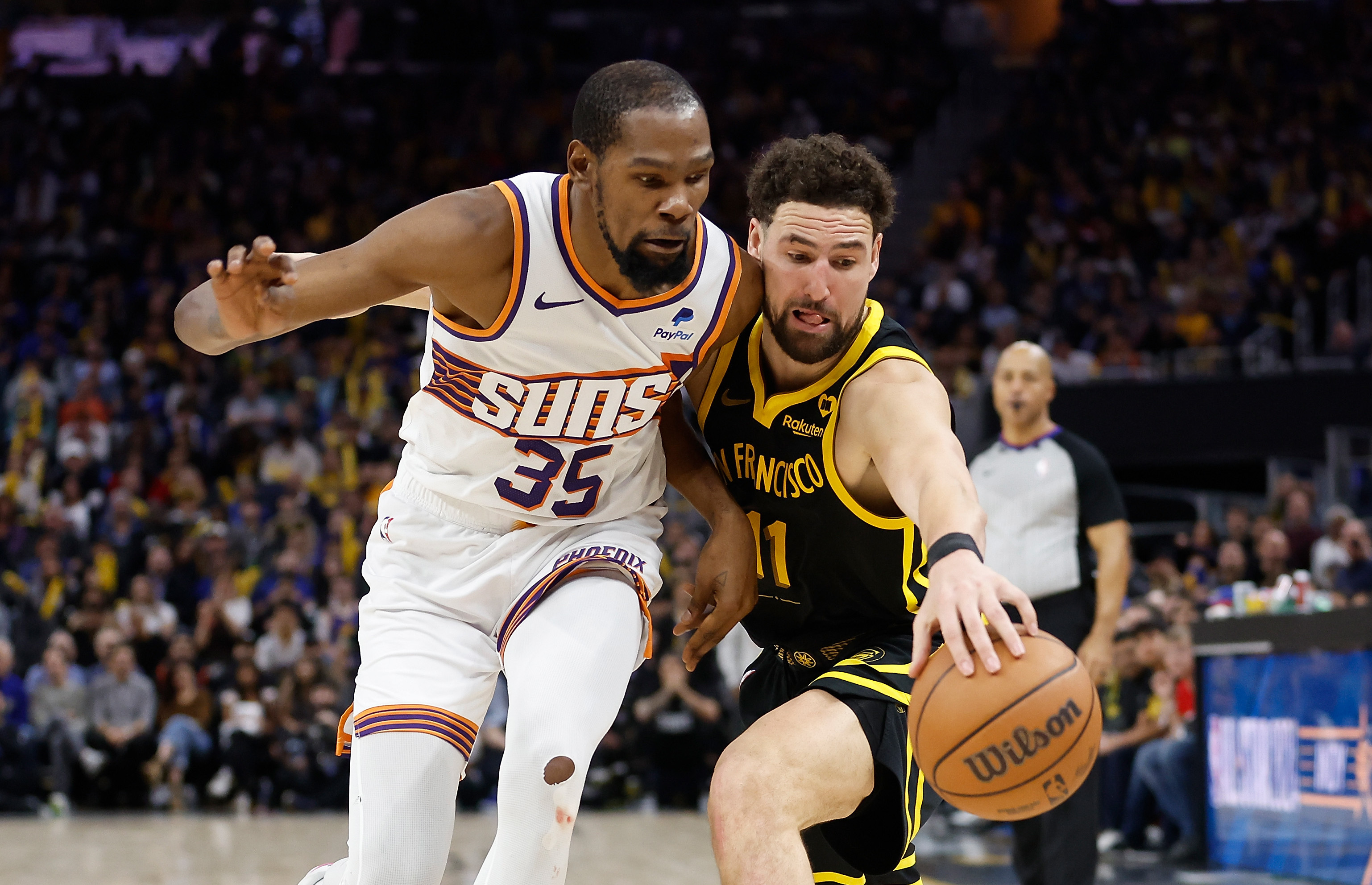 Kevin Durant in a Suns jersey defends Klay Thompson in a Warriors jersey during a basketball game.