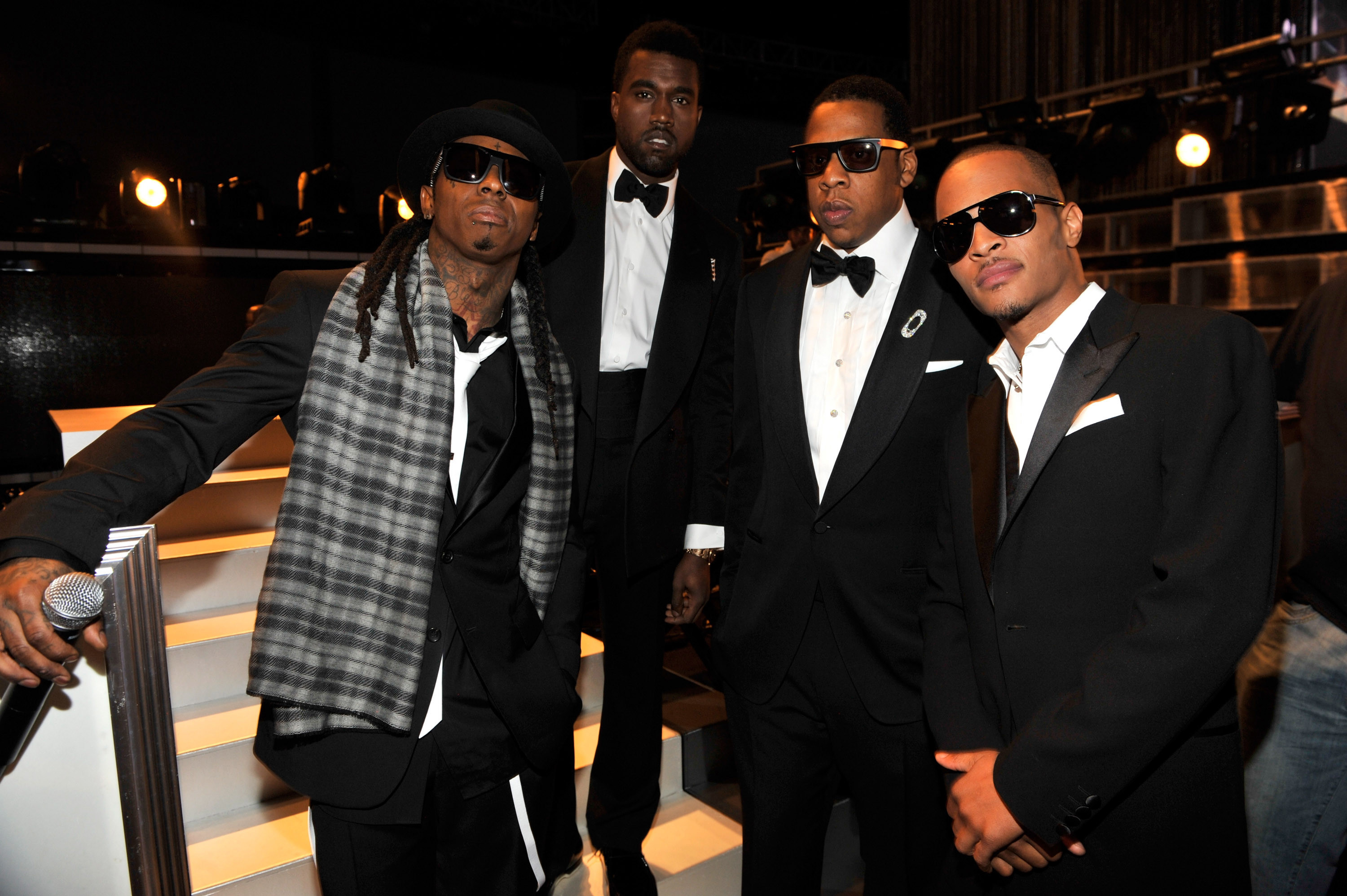 Lil Wayne, Kanye West, Jay-Z, and T.I. in tuxedos, standing together at the Grammys wearing sunglasses.