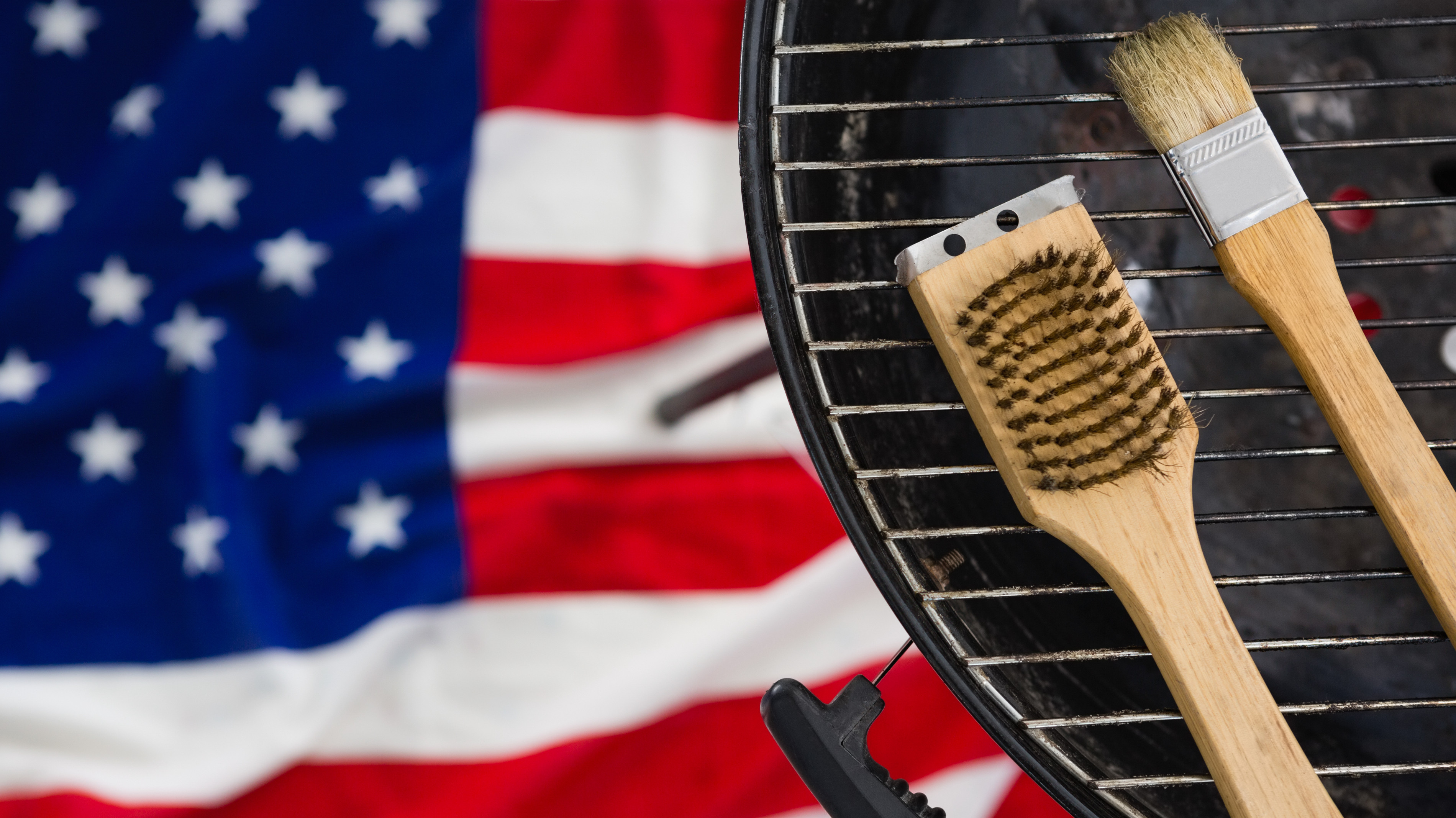 Close-up of basting brush arranged on barbeque against American flag.