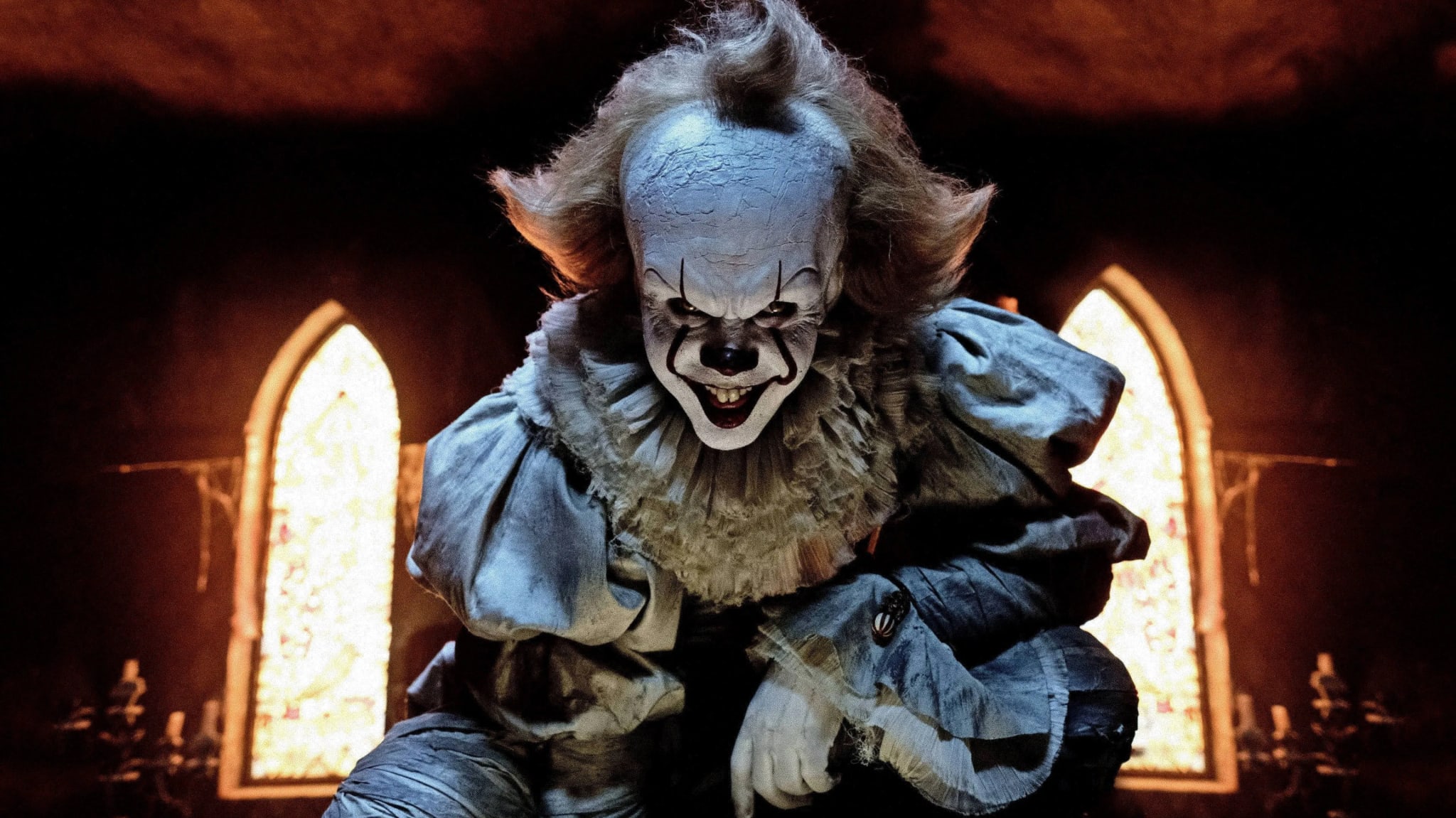Pennywise the clown, from the horror film "It," crouches menacingly with a sinister smile, set against a backdrop of dim, arched windows.