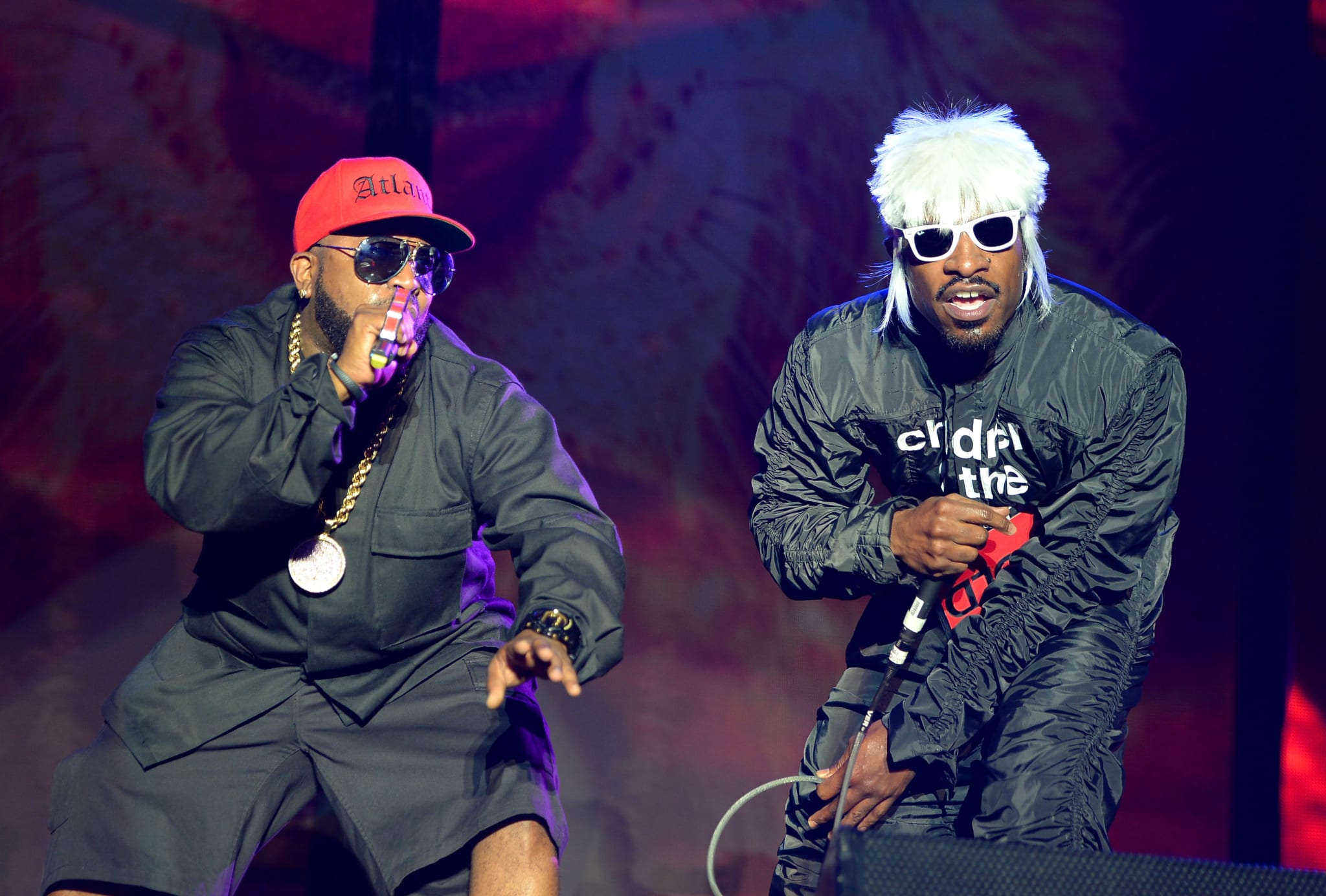 Big Boi and André 3000 performing on stage, wearing distinctive outfits.