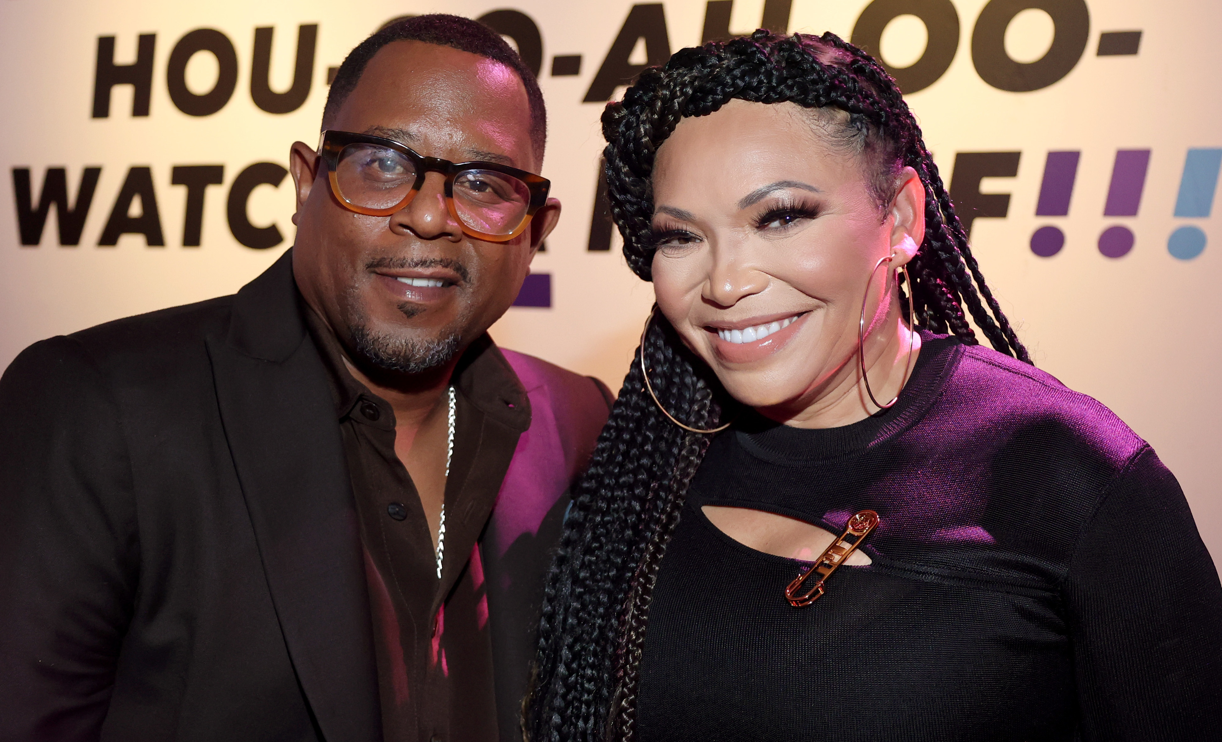 Martin Lawrence and Tisha Campbell smiling at an event, with a colorful backdrop.