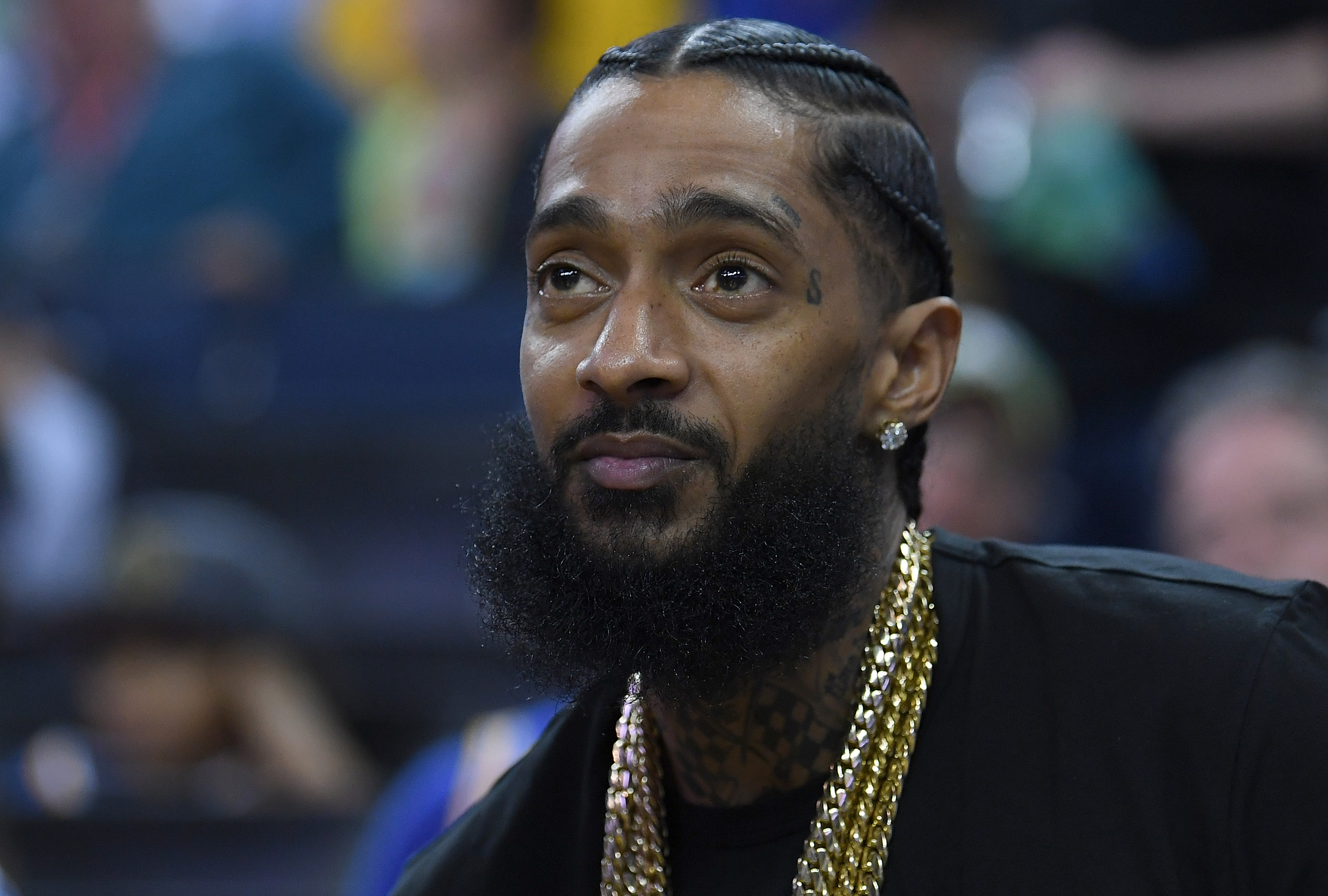 Rapper Nipsey Hussle sitting at courtside looks on during an NBA basketball game between the Milwaukee Bucks and Golden State Warriors at ORACLE Arena on March 29, 2018 in Oakland, California. NOTE TO USER: User expressly acknowledges and agrees that, by downloading and or using this photograph, User is consenting to the terms and conditions of the Getty Images License Agreement. 