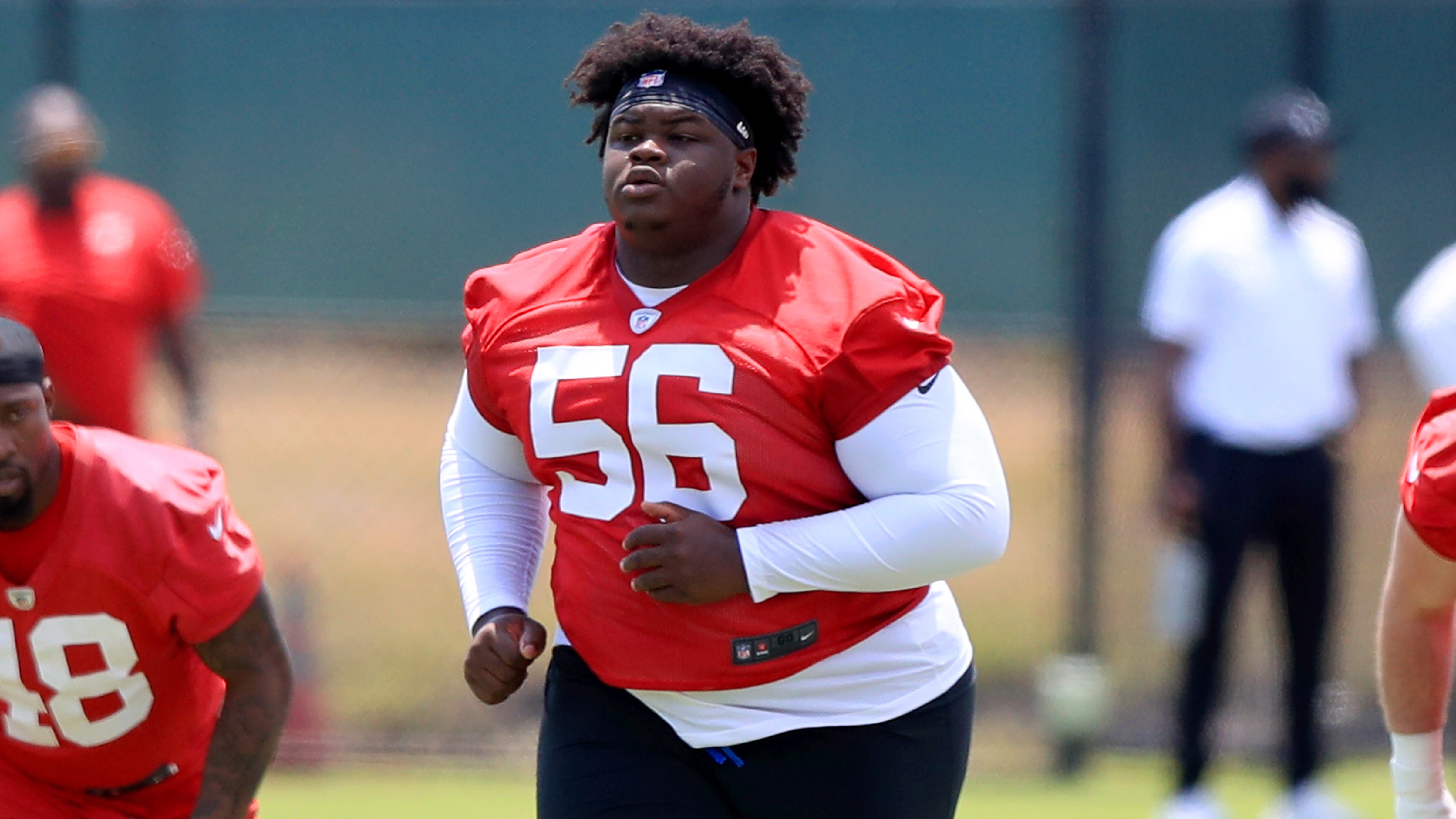 Desmond Watson wearing a red jersey with the number 56 is running during practice on a field.