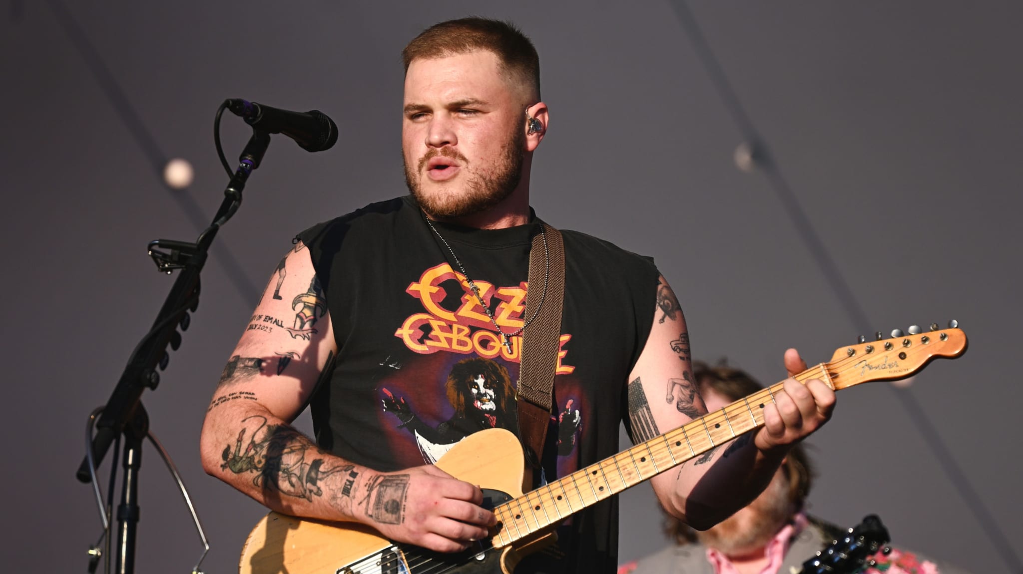 Zach Bryan playing guitar on stage.