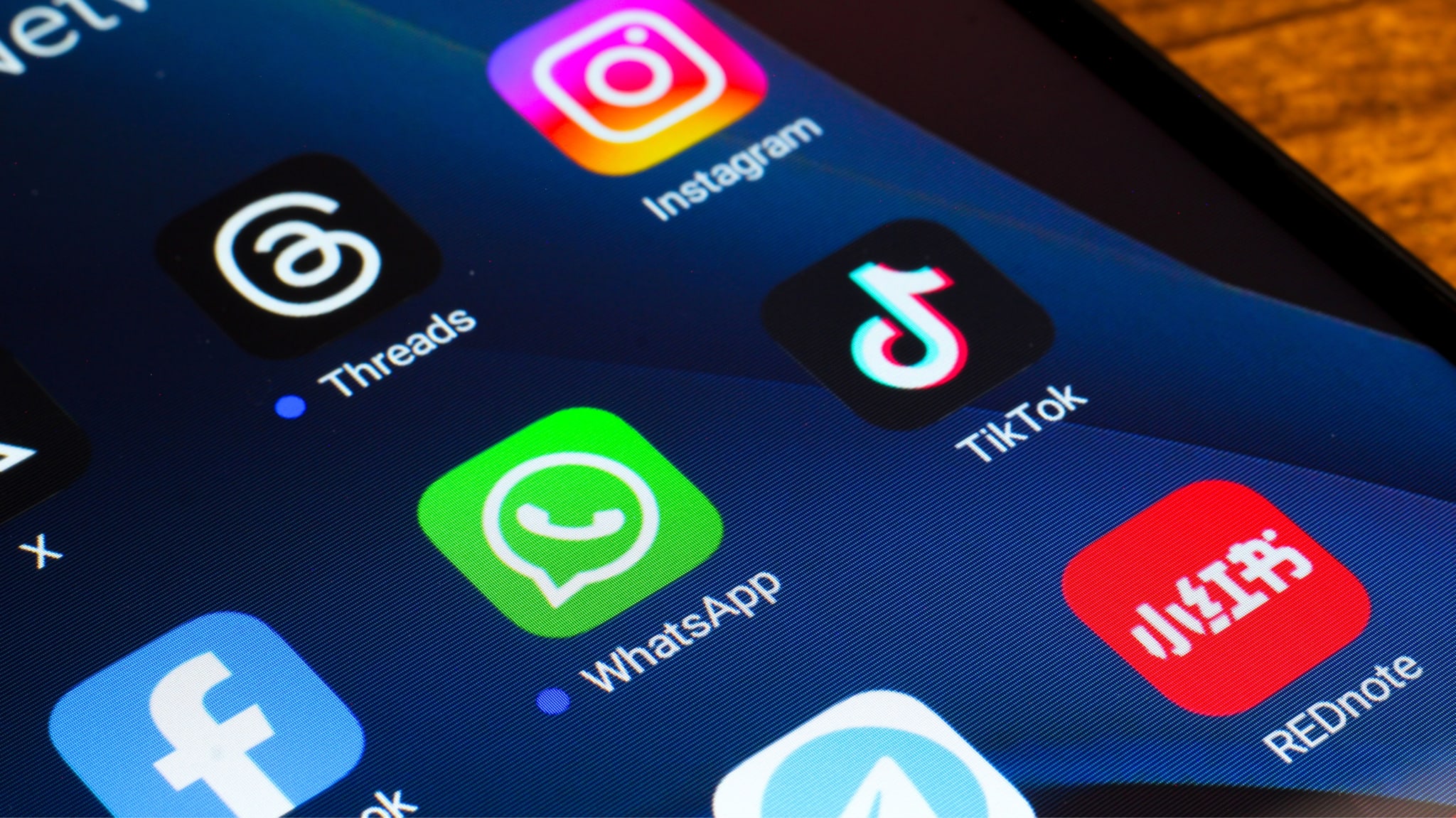 Close-up of a smartphone screen displaying various app icons, including Instagram, TikTok, WhatsApp, Threads, and REDnote.