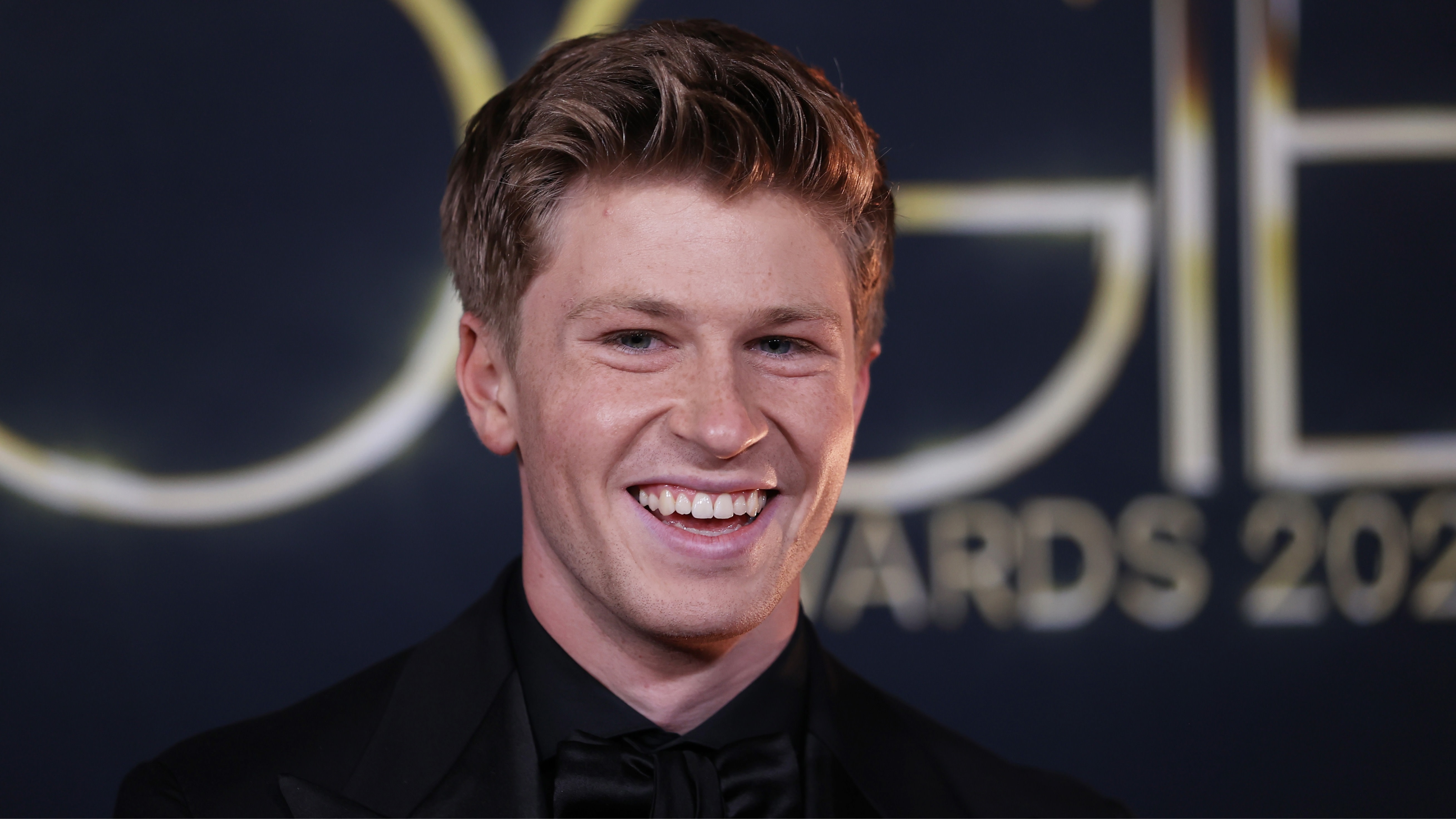 Robert Irwin smiling at an event with a blurred "Awards 2023" sign in the background.