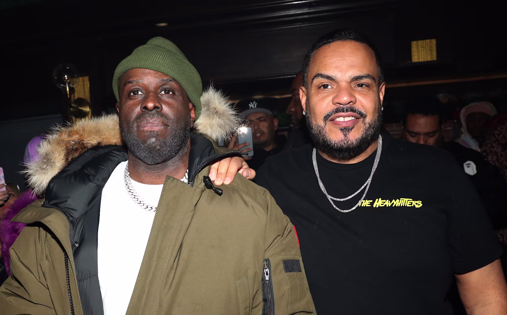 Funk Flex in a green jacket and beanie, DJ Enuff in a black T-shirt. People are in the background.