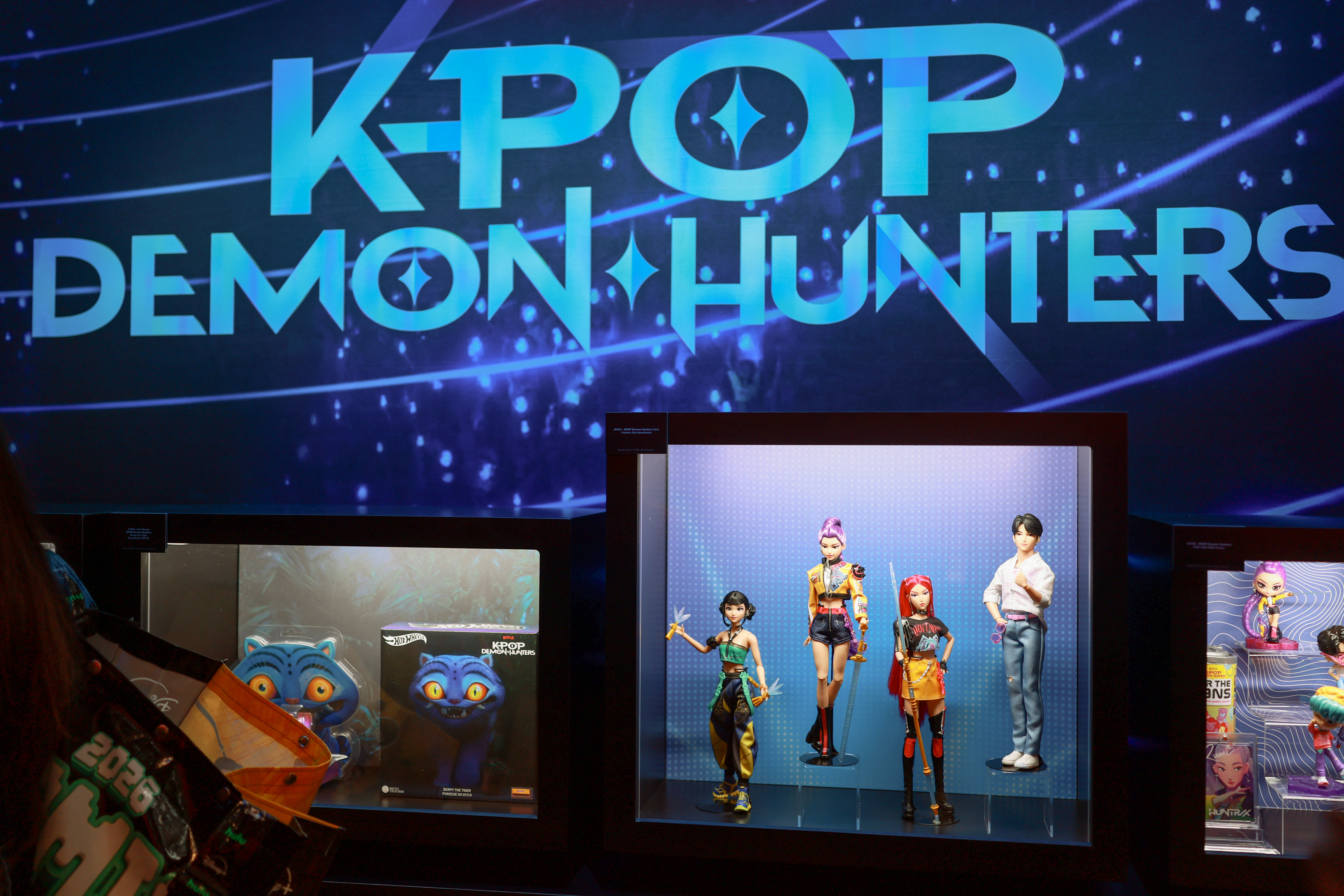 Display of "K-Pop Demon Hunters" figures, featuring colorful characters in dynamic poses, set against a vibrant backdrop.