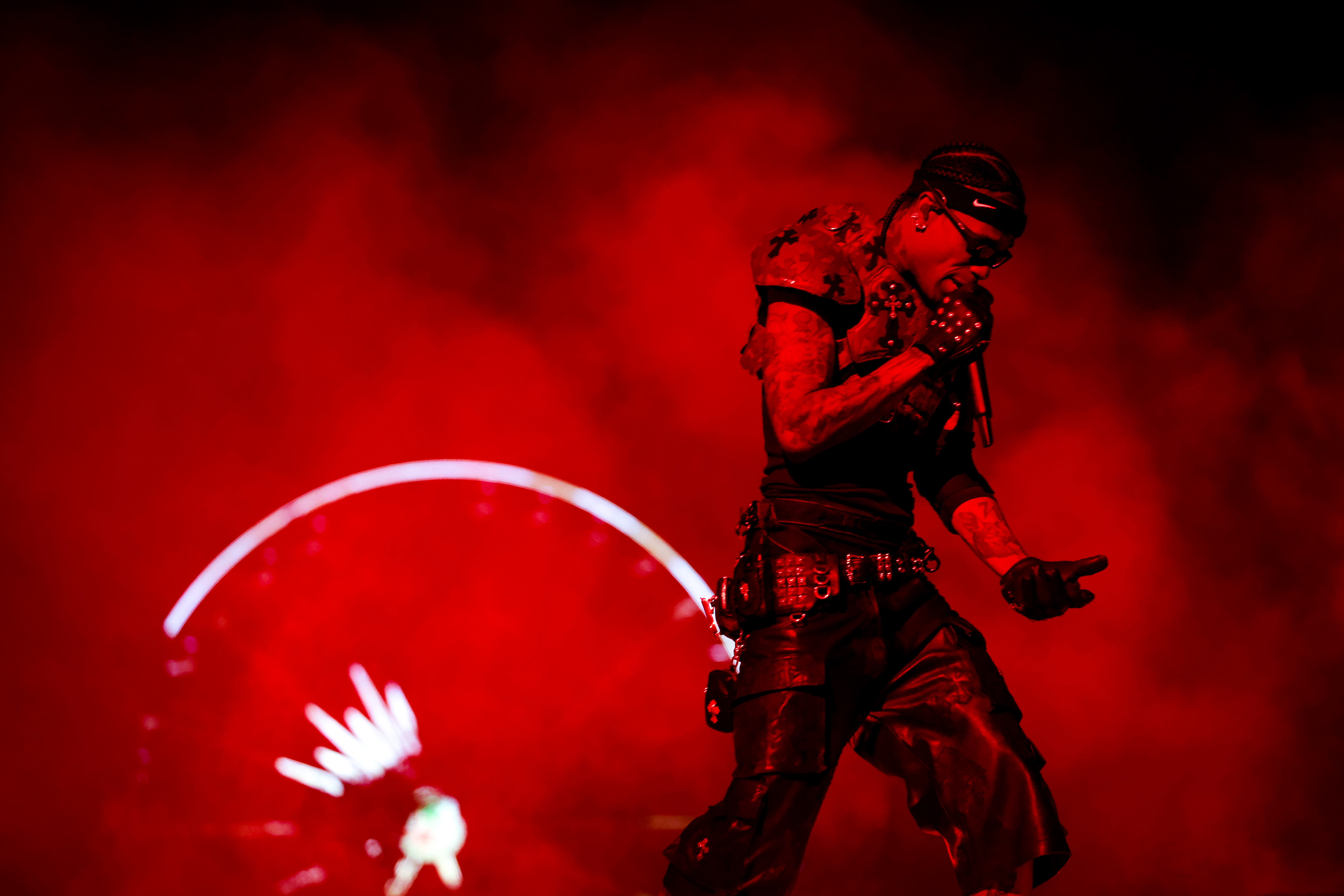 Travis Scott on stage in a dramatic red-lit scene, with a Ferris wheel in the background. This is from his Coachella 2025 performance. 