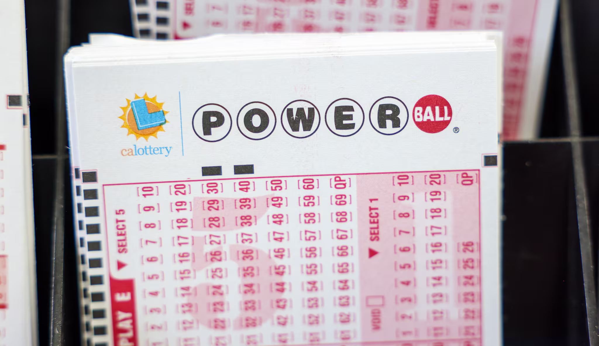 Stack of California Powerball lottery tickets in a display.