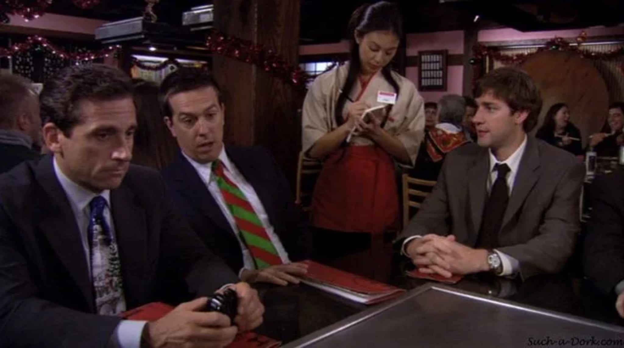 Steve Carell, Ed Helms, and John Krasinski in a restaurant scene from 'The Office,' with a waitress taking their order.