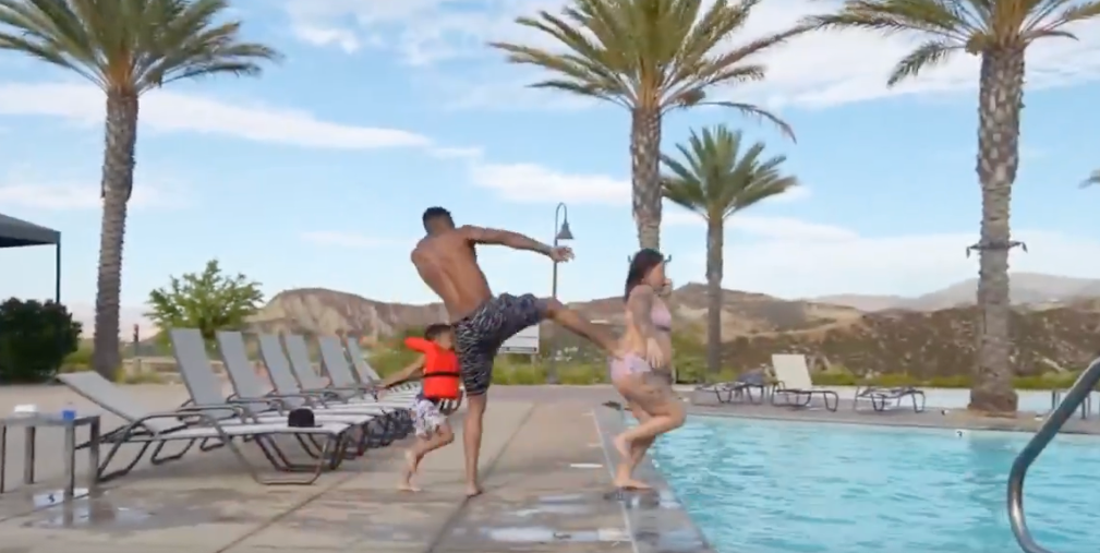 Screenshot of Blueface playfully kicking Nevaeh Akira into a pool on his Kick stream.