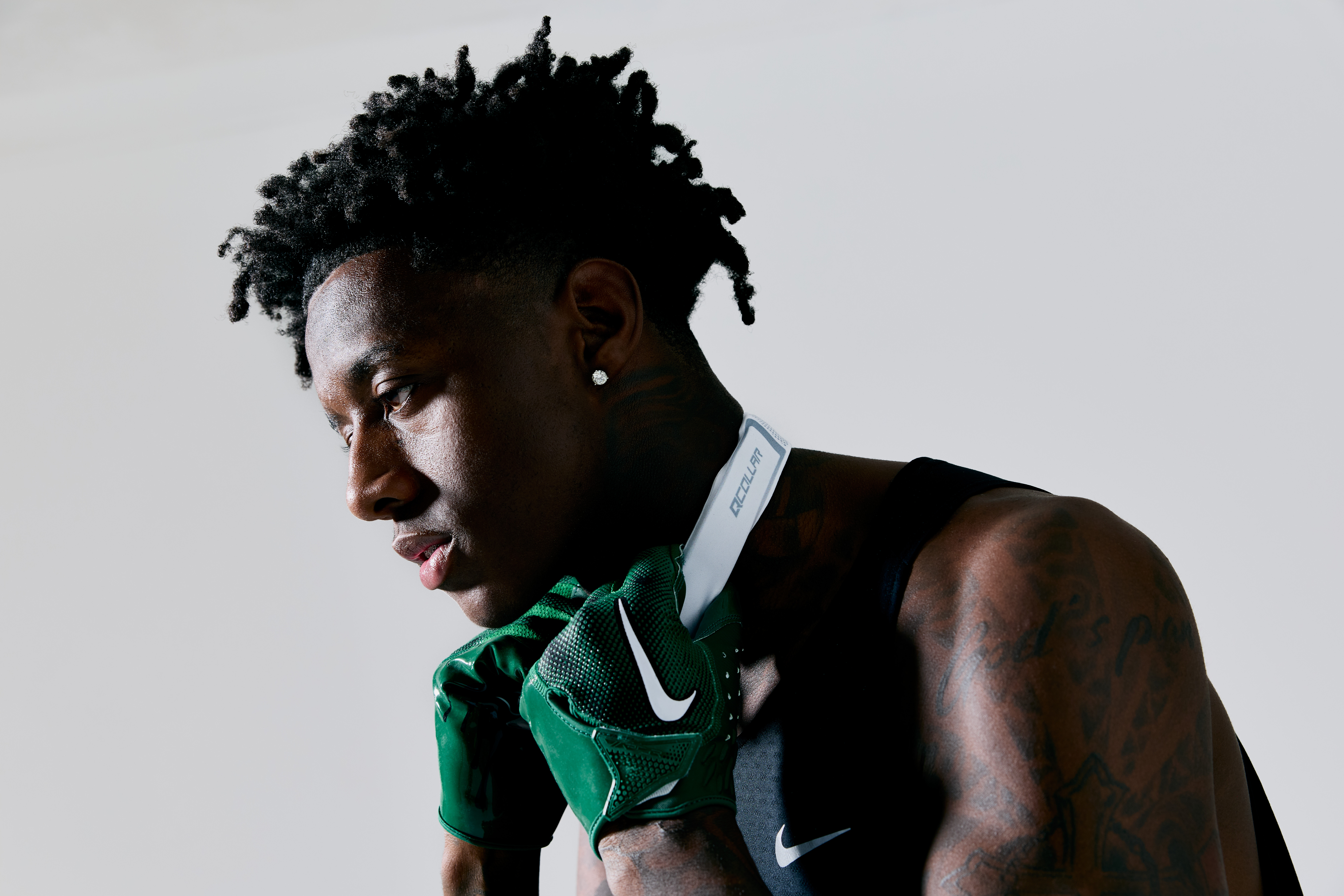 Sauce Gardner wearing green Nike gloves and a black tank top, holding a white towel around his neck.