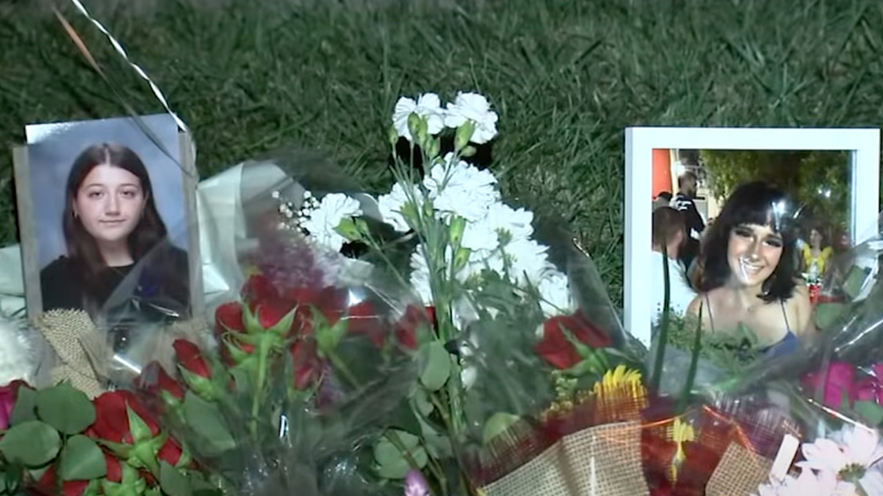 Photos of two young women surrounded by bouquets of flowers on grass, creating a memorial.