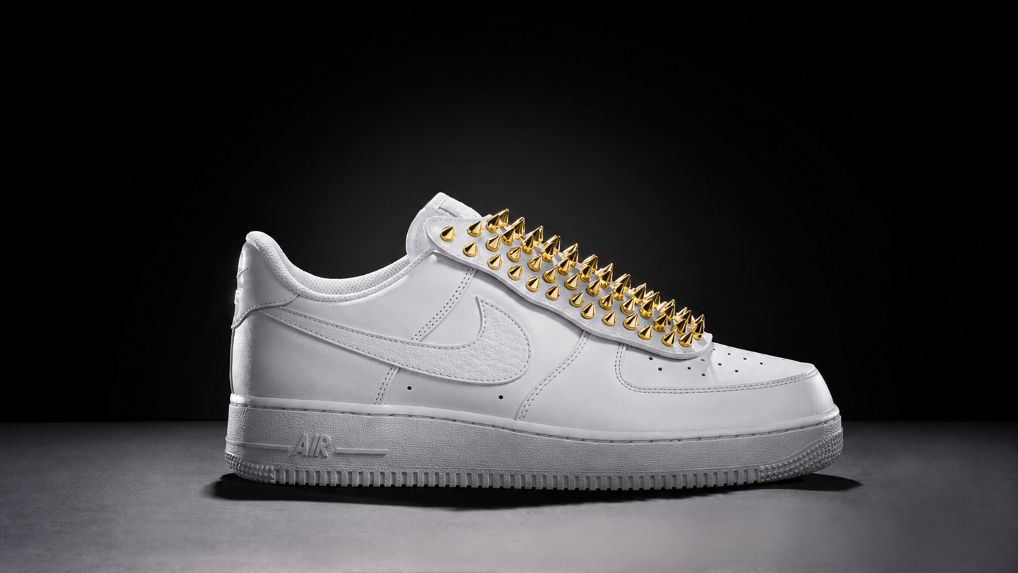 White Nike Air Force 1 sneaker with gold spikes on the laces.