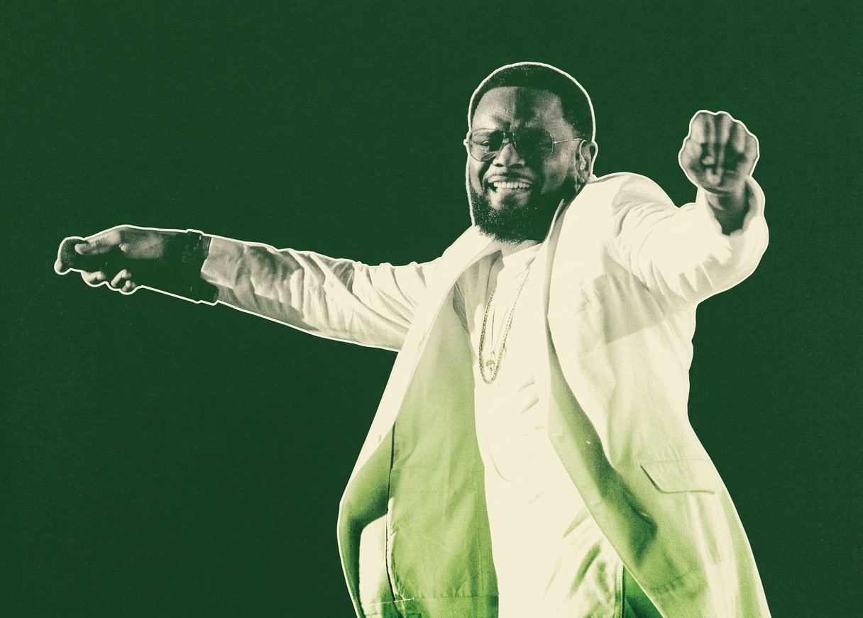 Carl Thomas in a white outfit energetically performing on stage, holding a microphone, with a joyful expression.