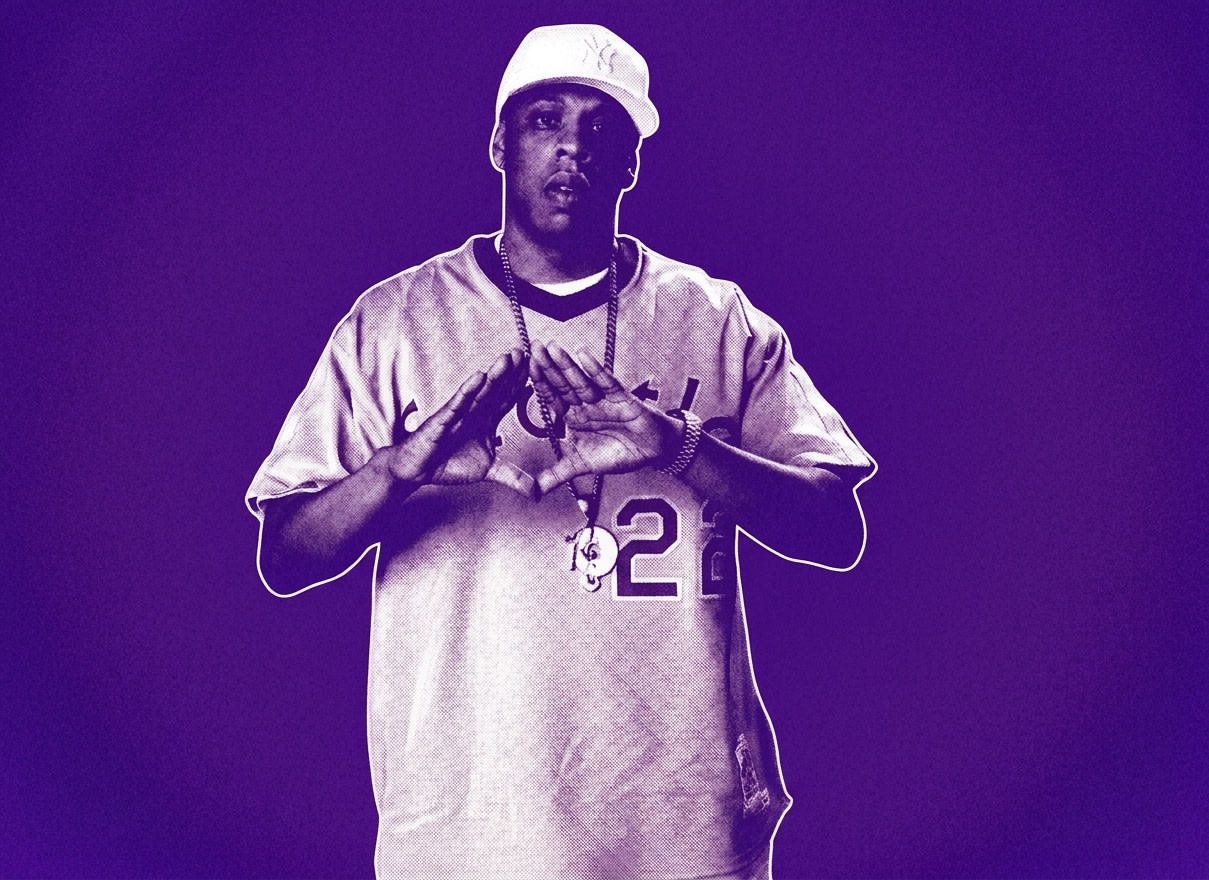 Jay-Z wearing a light blue sports jersey and necklace, making a diamond hand gesture against a red and brown backdrop.