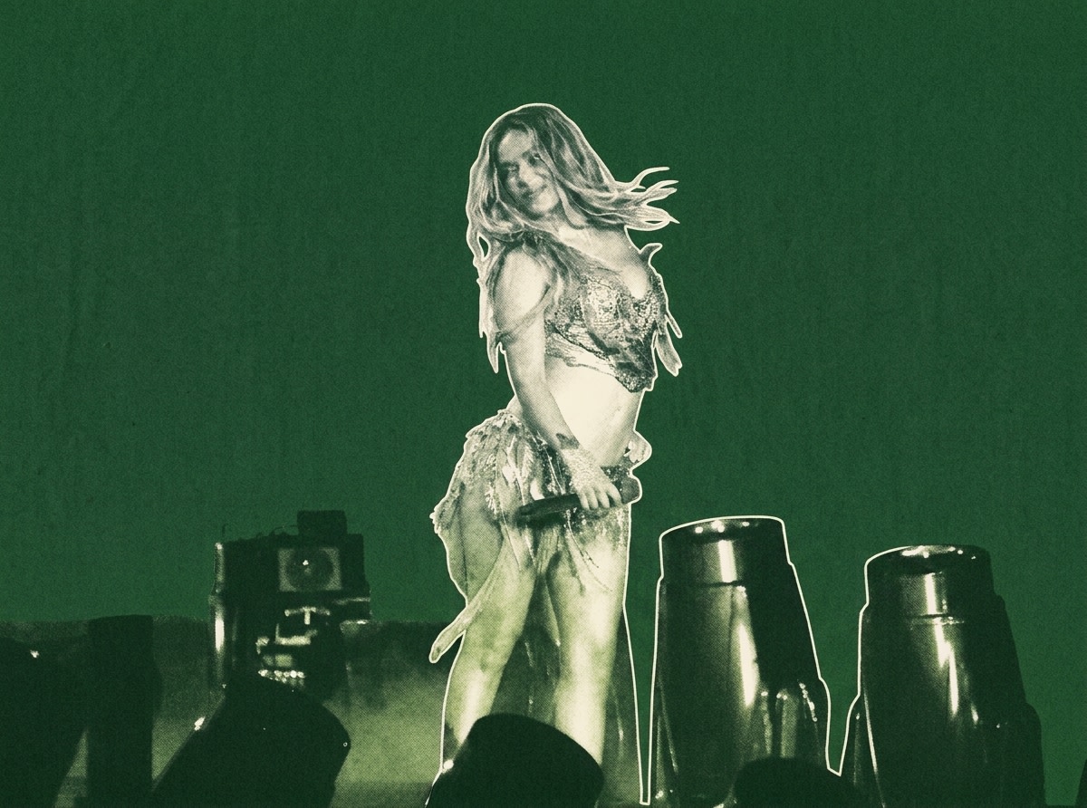 Karol G on stage in a dynamic pose, holding a microphone, with a green background and stage lights.