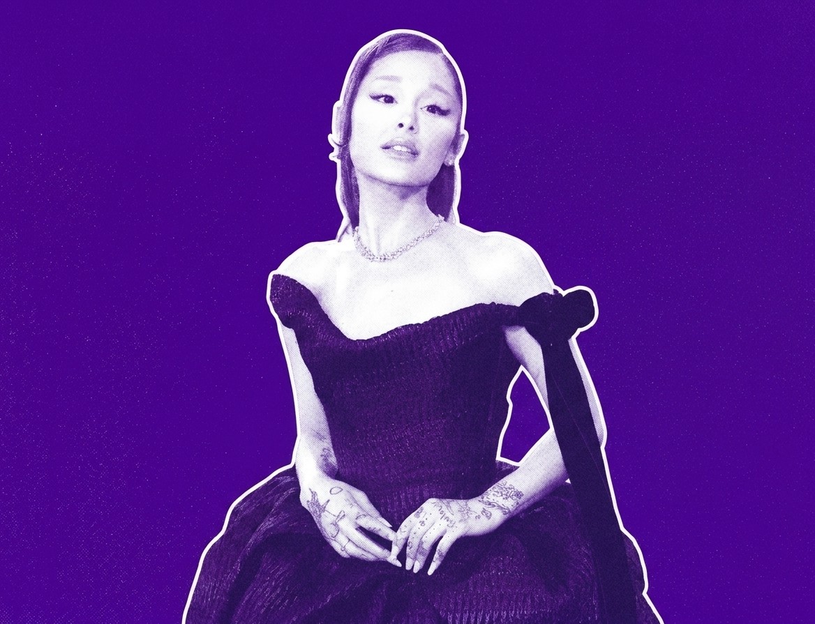 Ariana Grande in a stylized purple-toned image, wearing an elegant off-shoulder dress and displaying tattoos on her hands.