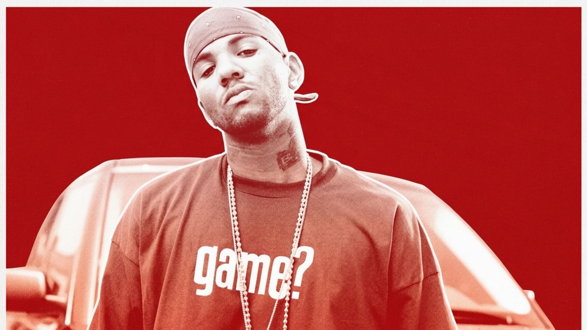 Rapper The Game wearing a bandana and "game?" shirt, standing in front of a car.