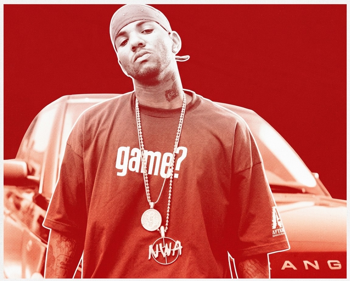 Rapper The Game wearing a bandana and "game?" shirt, standing in front of a car.