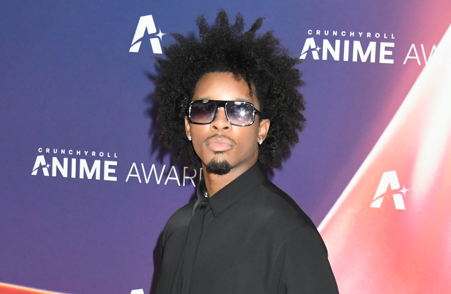 D4vd with an afro hairstyle and sunglasses wearing a black outfit at the Crunchyroll Anime Awards.