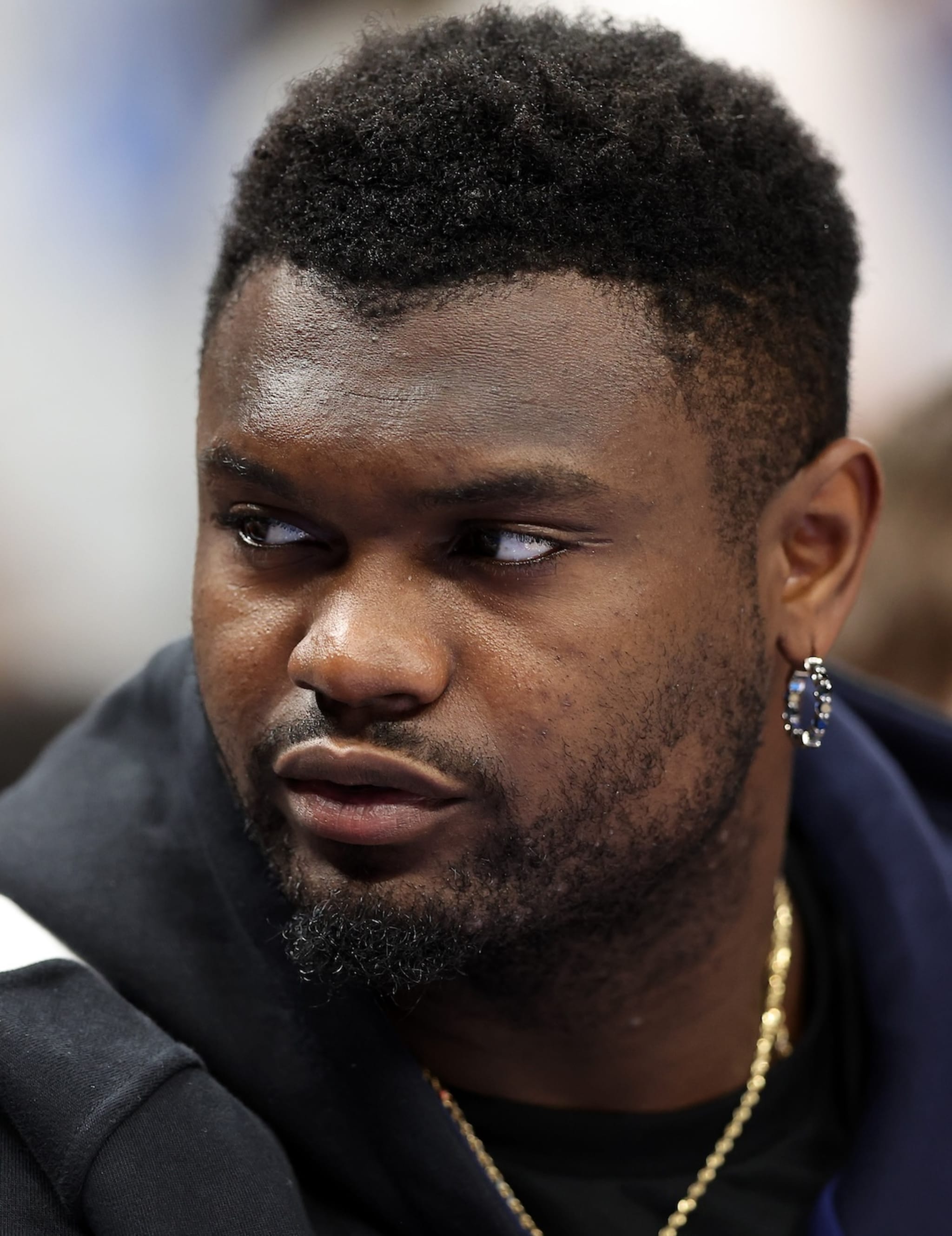 Zion Williamson, wearing a black hoodie and a gold chain, looking to the side.