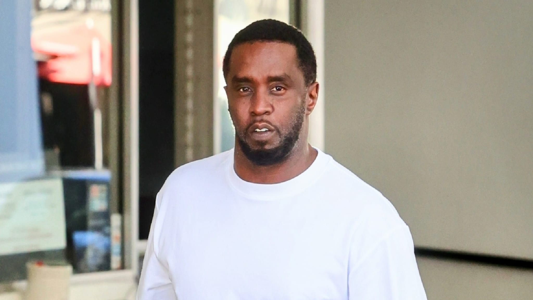 Sean Combs in a white shirt walking outside a building.