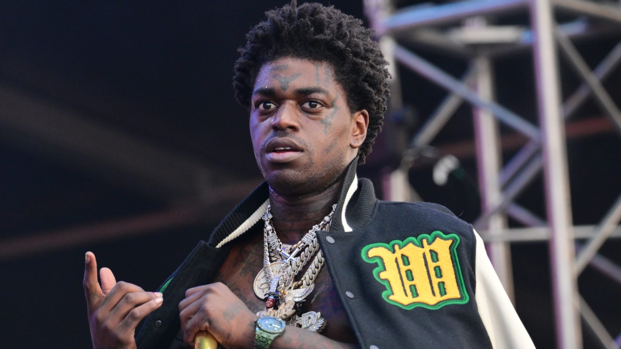 Kodak Black performing wearing silver chains and a letterman jacket.