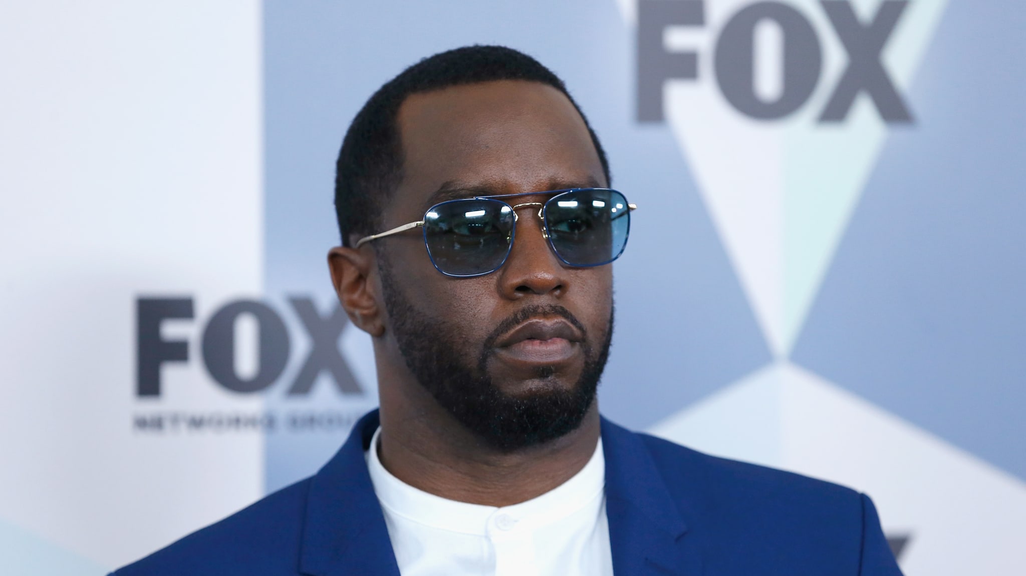 Sean "Diddy" Combs wearing sunglasses and a blue suit at a FOX event.