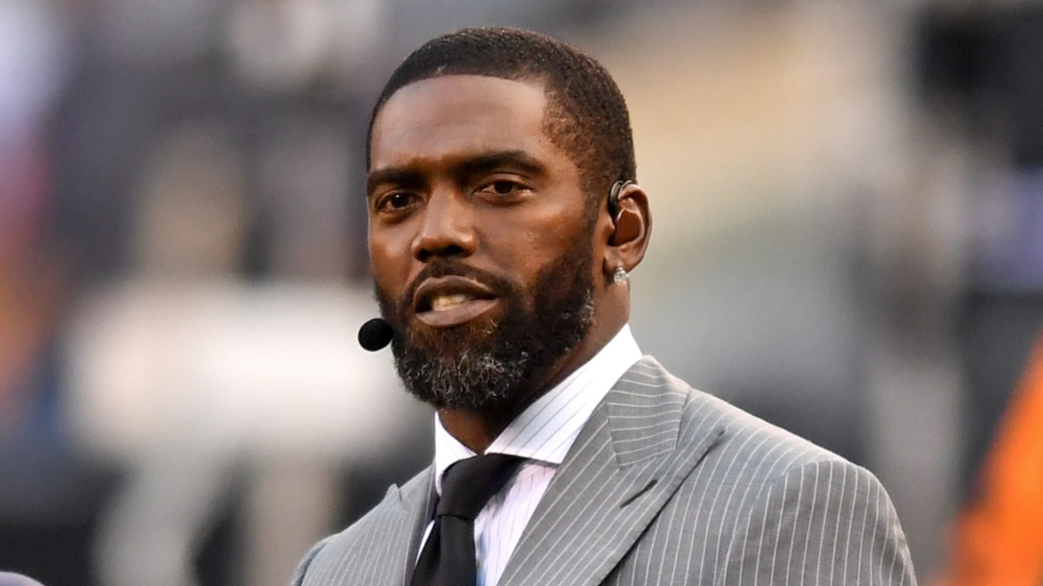 A man with a beard and earpiece in a gray pinstripe suit and tie.