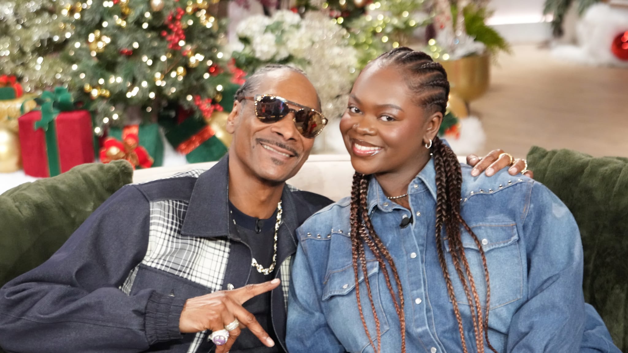 Snoop Dogg, wearing sunglasses and a plaid jacket, sits with a smiling woman in denim. Christmas decorations are in the background.BURBANK, CALIFORNIA - November 21: Snoop Dogg and Cori Broadus appear on "The Jennifer Hudson Show" airing December 2, 2024 in Burbank, California. 